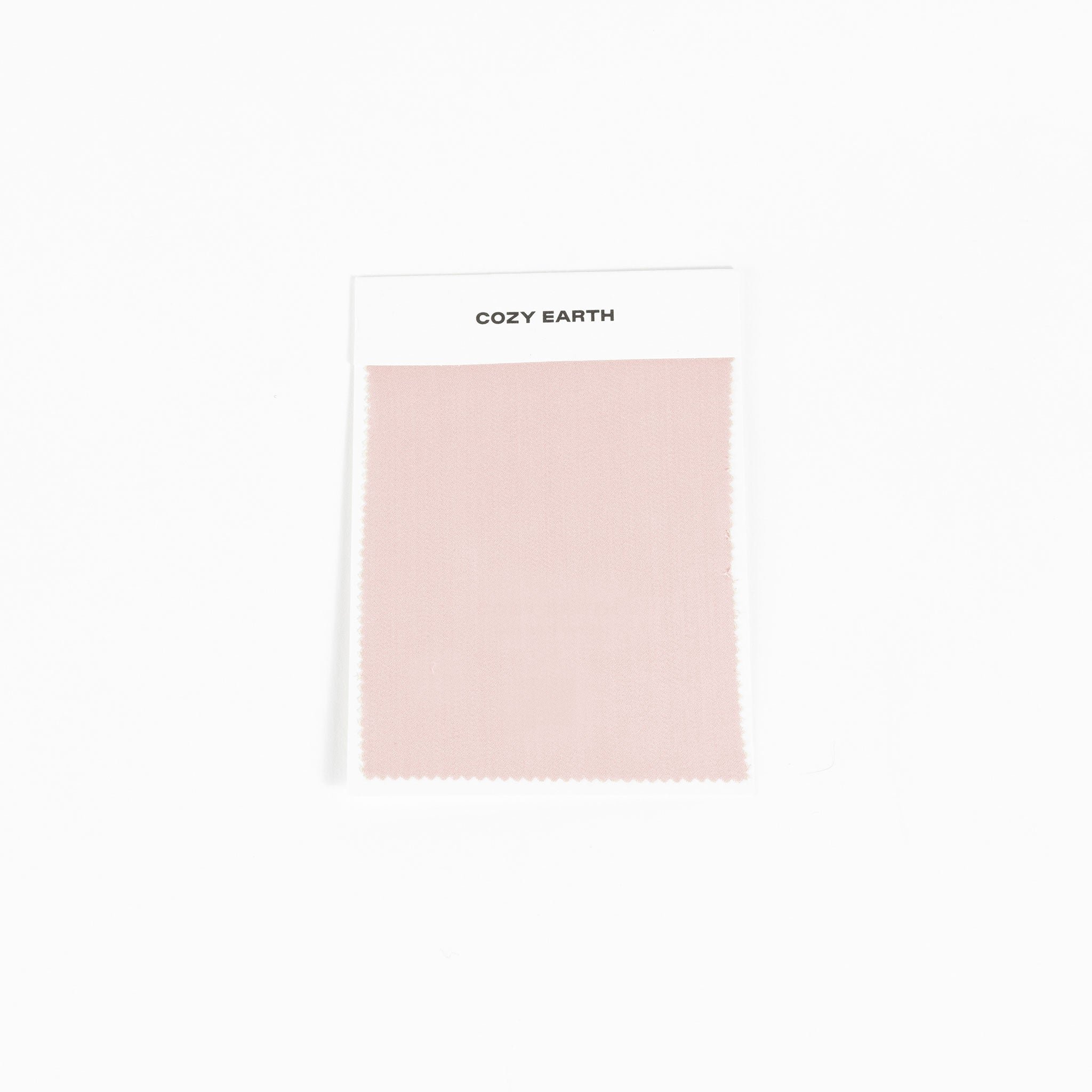 A sample swatch of Bamboo Sheet fabric from Cozy Earth, in light pink, is displayed on a white card against a white background.|Color:Peony