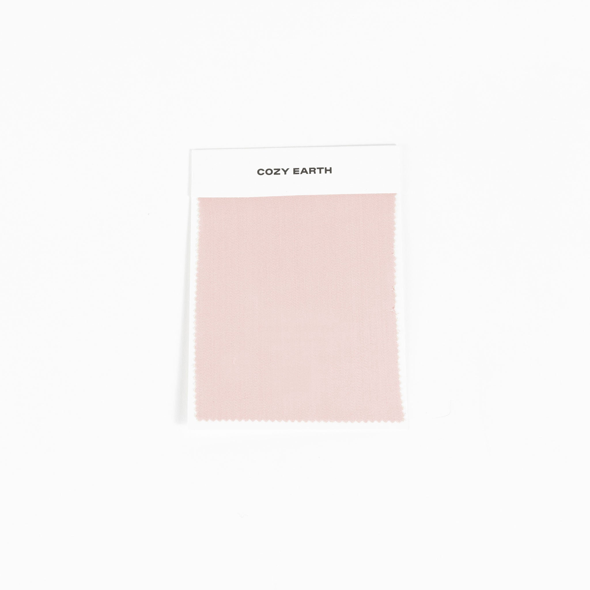 A sample swatch of Bamboo Sheet fabric from Cozy Earth, in light pink, is displayed on a white card against a white background.|Color:Peony