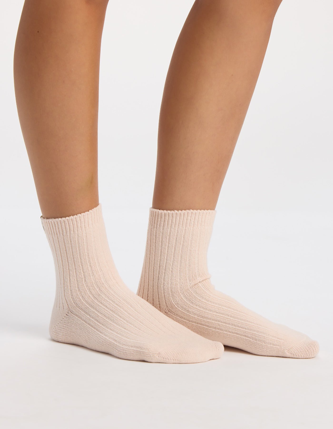 Someone wearing Cozy Earth's The Plush Modern Crew Sock in light beige stands with both feet flat on a white surface.