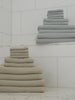 Harbor Mist and Sand colored waffle bath bundles rest on a marble floor in a shower room. Close ups of the towels can be seen