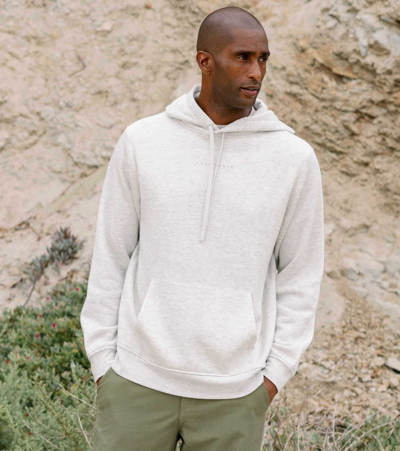 man in heather grey city scape hoodie with rocky background