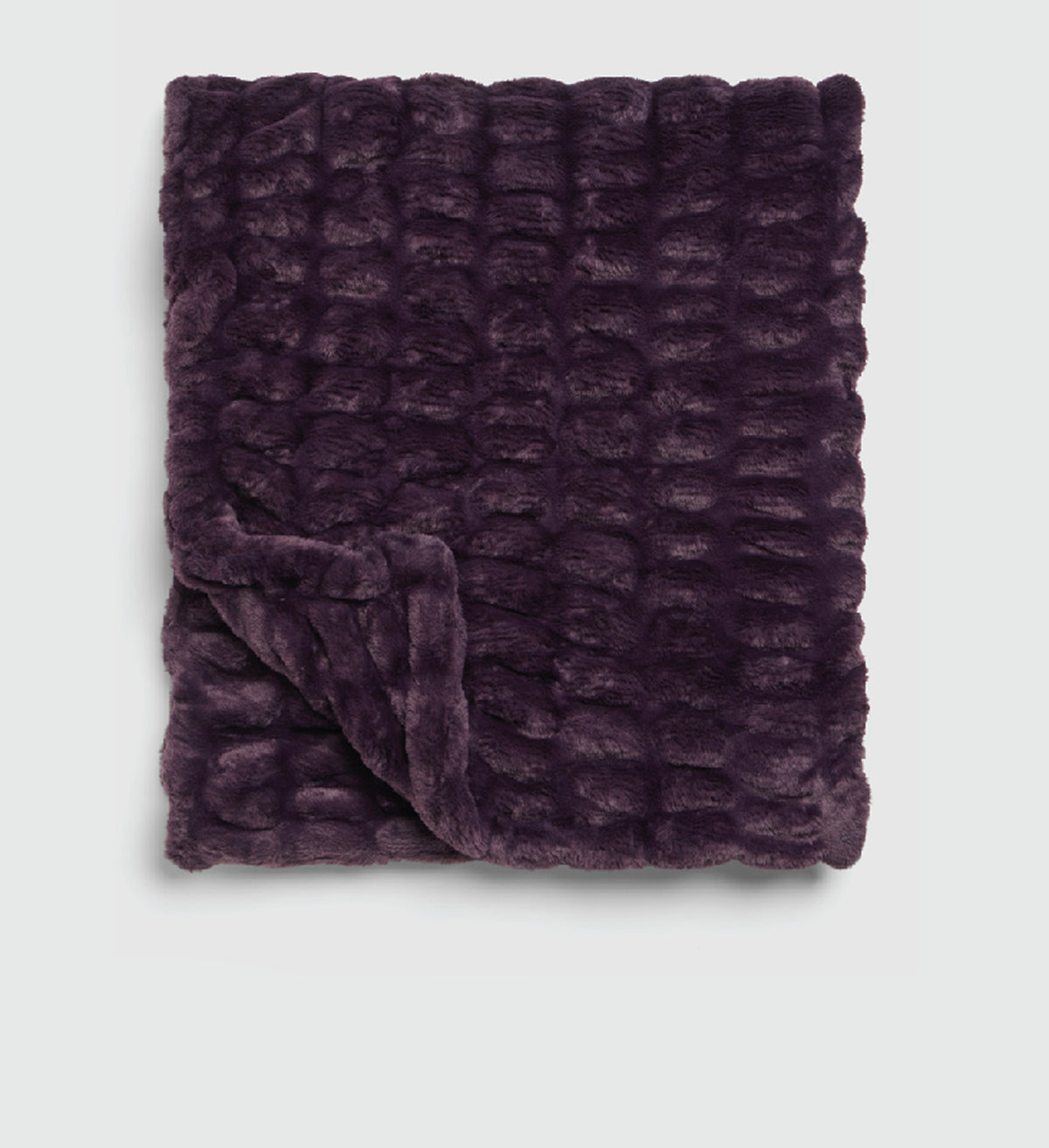 A dark purple textured faux fur throw blanket with a ribbed, wavy pattern, folded over in the bottom left corner against a light gray background.
