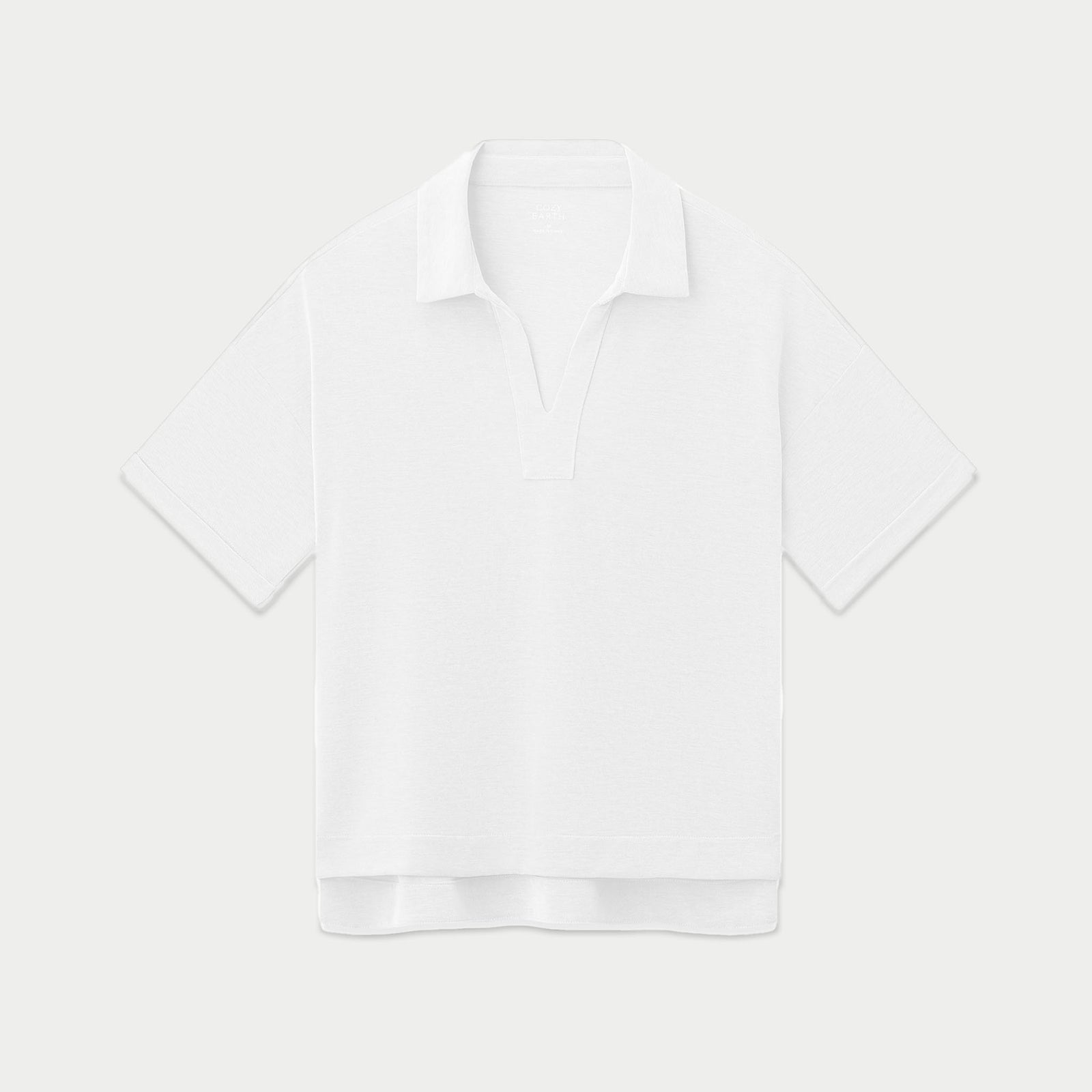 The Women's Modern Modal Polo by Cozy Earth is a white, short-sleeve polo shirt with a slightly loose fit. It showcases a relaxed collar and an open V-neck style, and is displayed flat on a plain, light background.