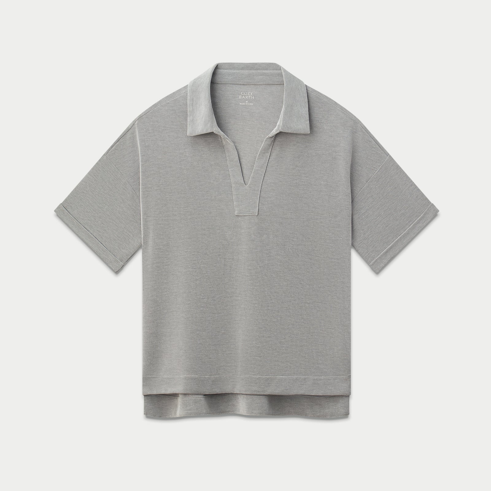A Women's Modern Modal Polo by Cozy Earth, shown flat on a white background. The light gray short-sleeved polo shirt features a split-V neckline, a relaxed fit, and a slightly longer back hem.