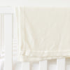Ivory Cloud Knit Baby Blanket draped over crib |Color:Ivory
