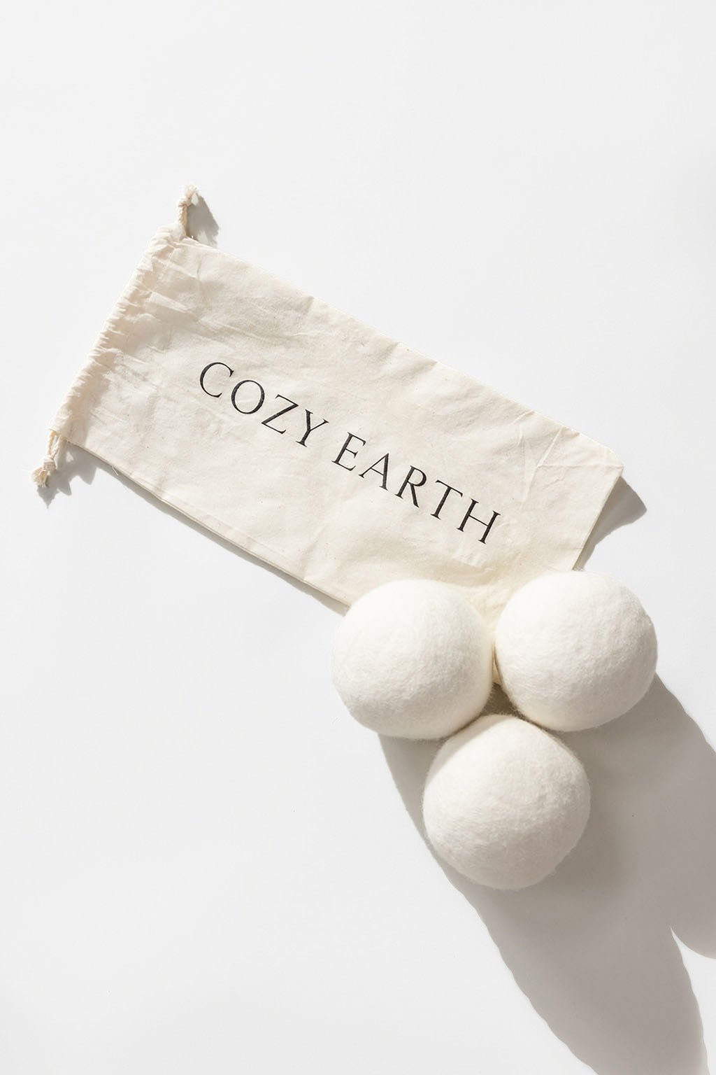 Wool Dryer Balls with storage bag resting on a white background.