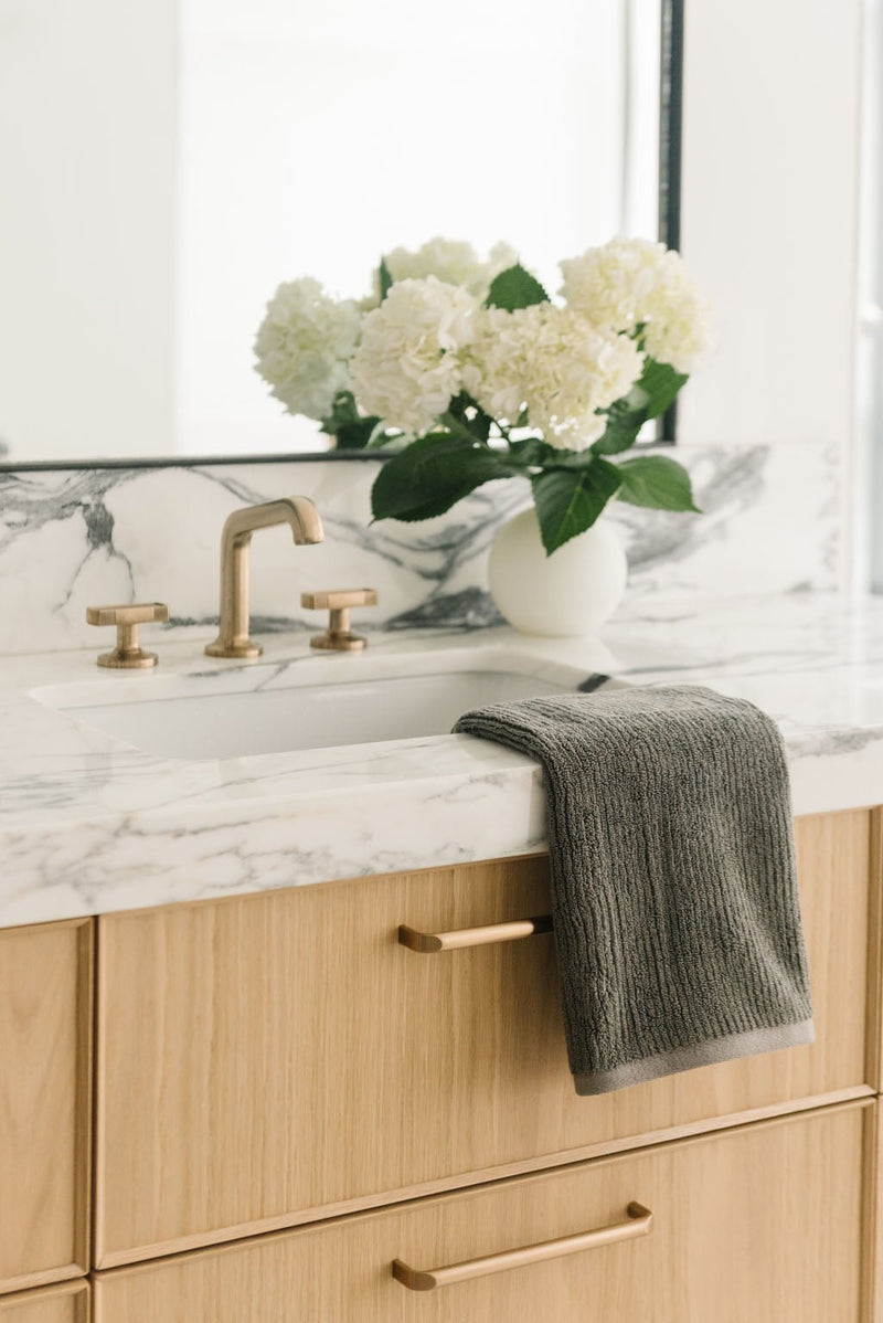 Ribbed Terry Hand Towel in the color Charcoal. Photo of Ribbed Terry Hand Towel taken with the Ribbed Terry Hand Towel resting on a bathroom sink.