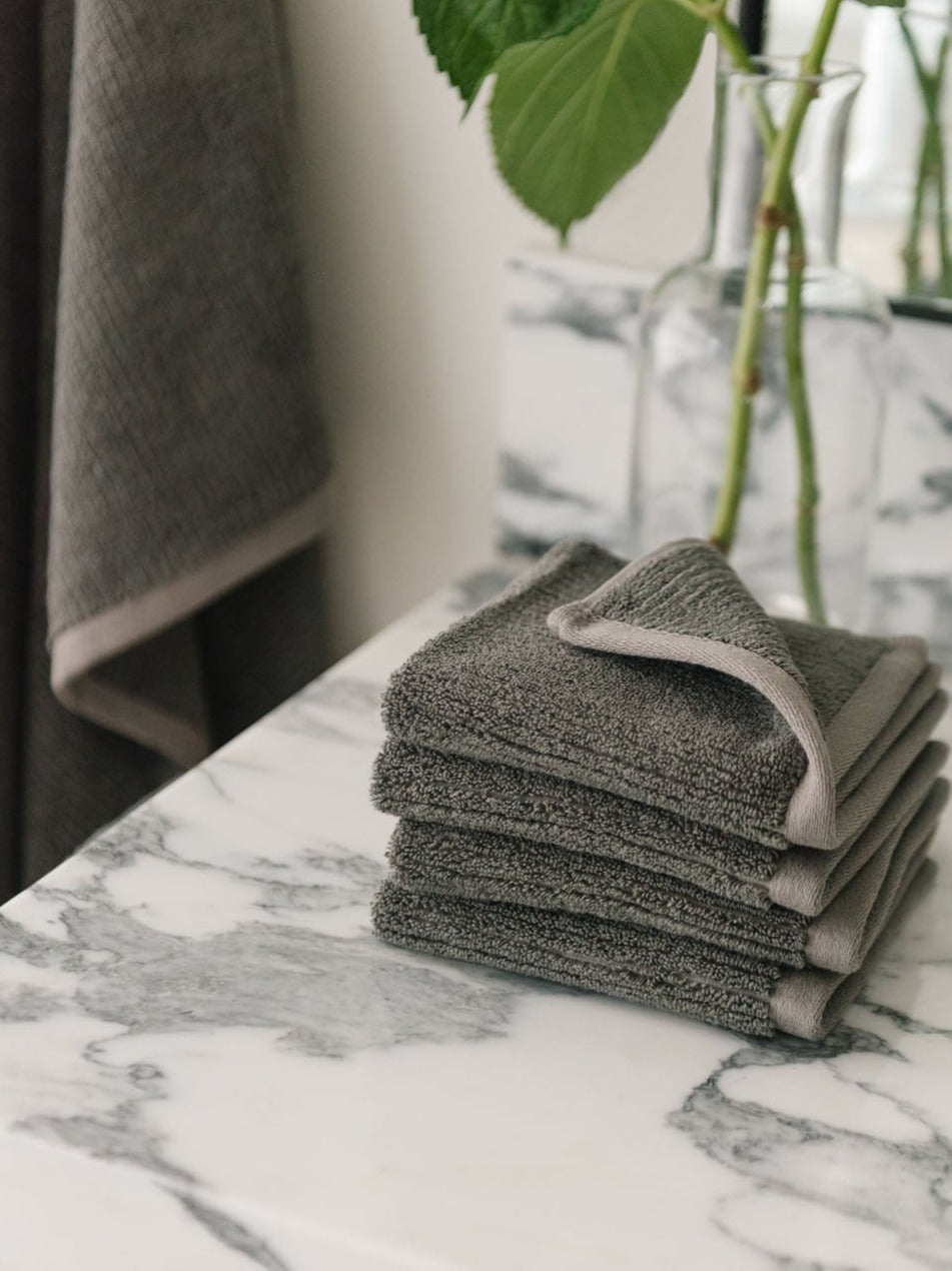 Ribbed Terry Wash Cloths in the color Charcoal. Photo of product taken on a white marble sink. 