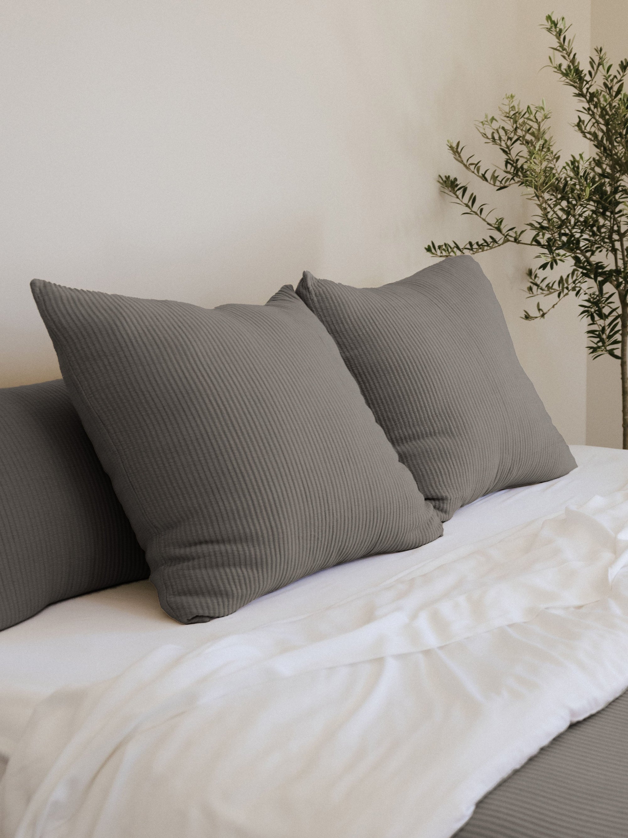 Charcoal coverlet shams on a white bed 