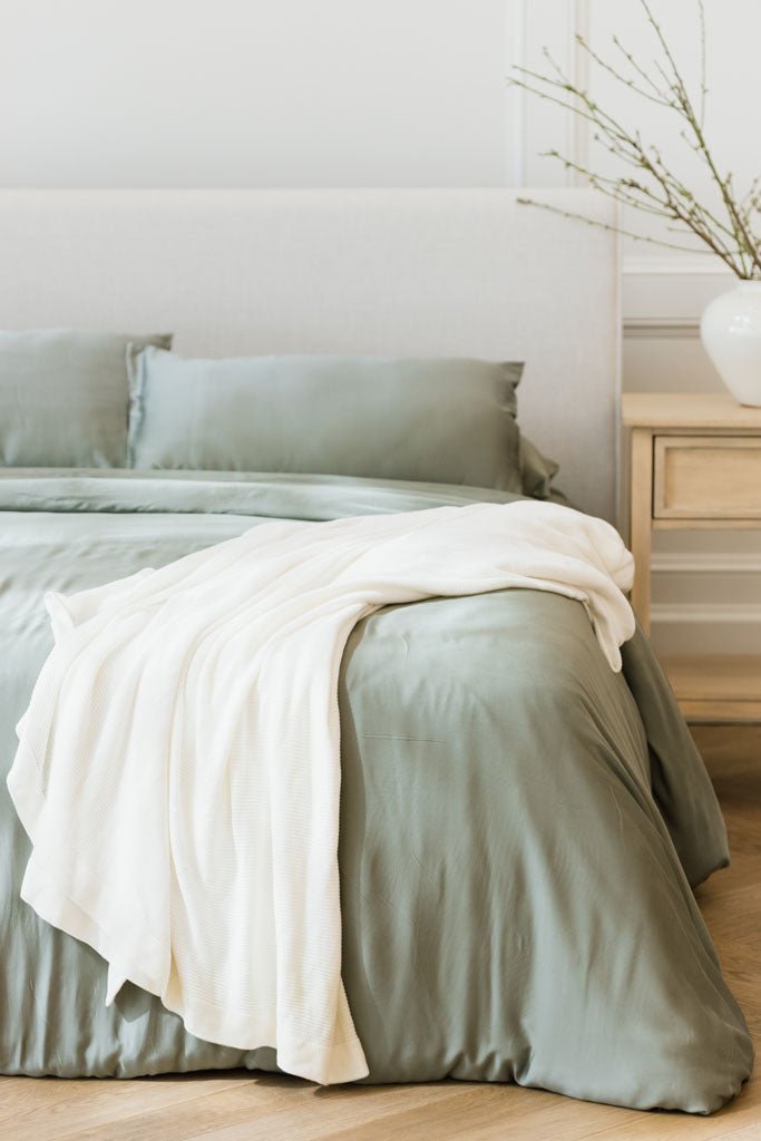 Ivory cloud knit blanket draped over bed with sage bedding |Color:Ivory