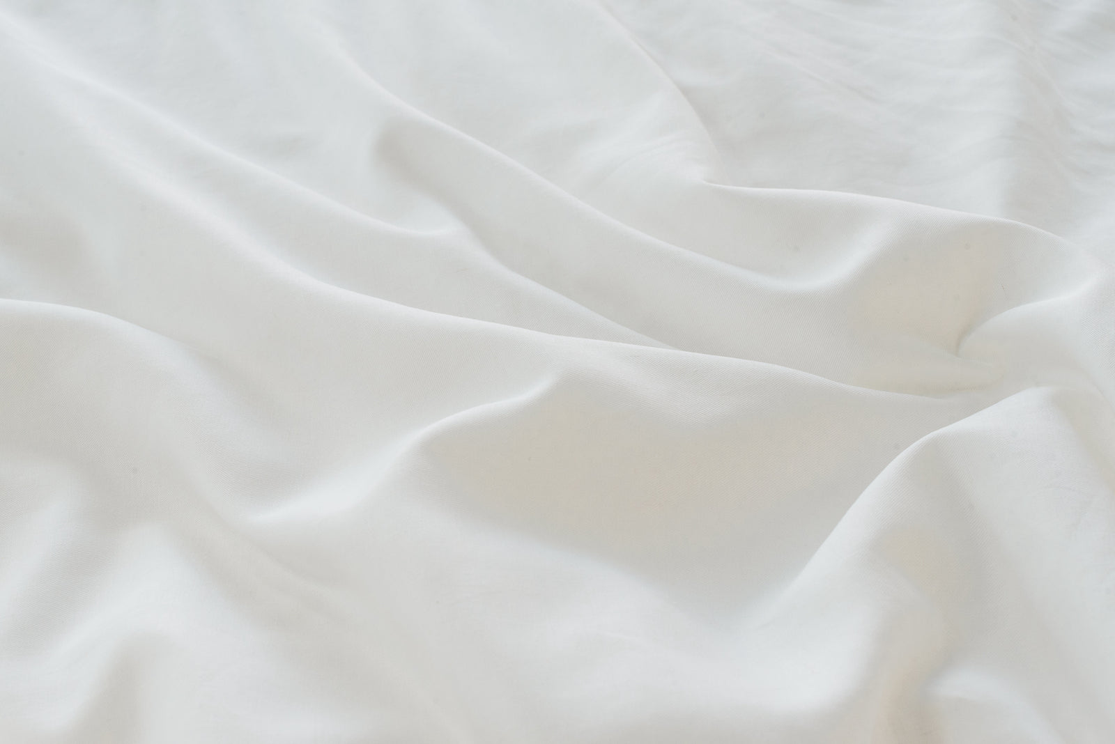 White Linen Bamboo Duvet Cover and comforter resting on a bed. Photo or product taken close up. 
