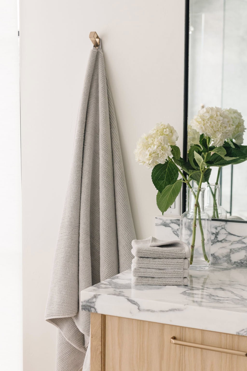 Ribbed Terry Bath Sheets in the color Light Grey. Photo of product taken in a bathroom next to a sink. 