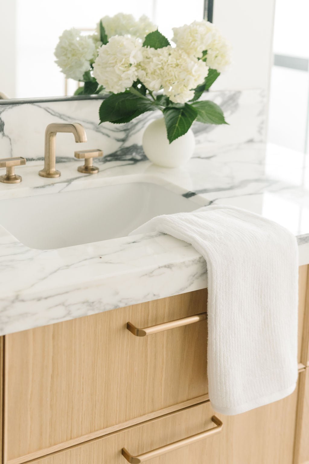 Ribbed Terry Hand Towel in the color White. Photo of Ribbed Terry Hand Towel taken with the Ribbed Terry Hand Towel resting on a bathroom sink. 