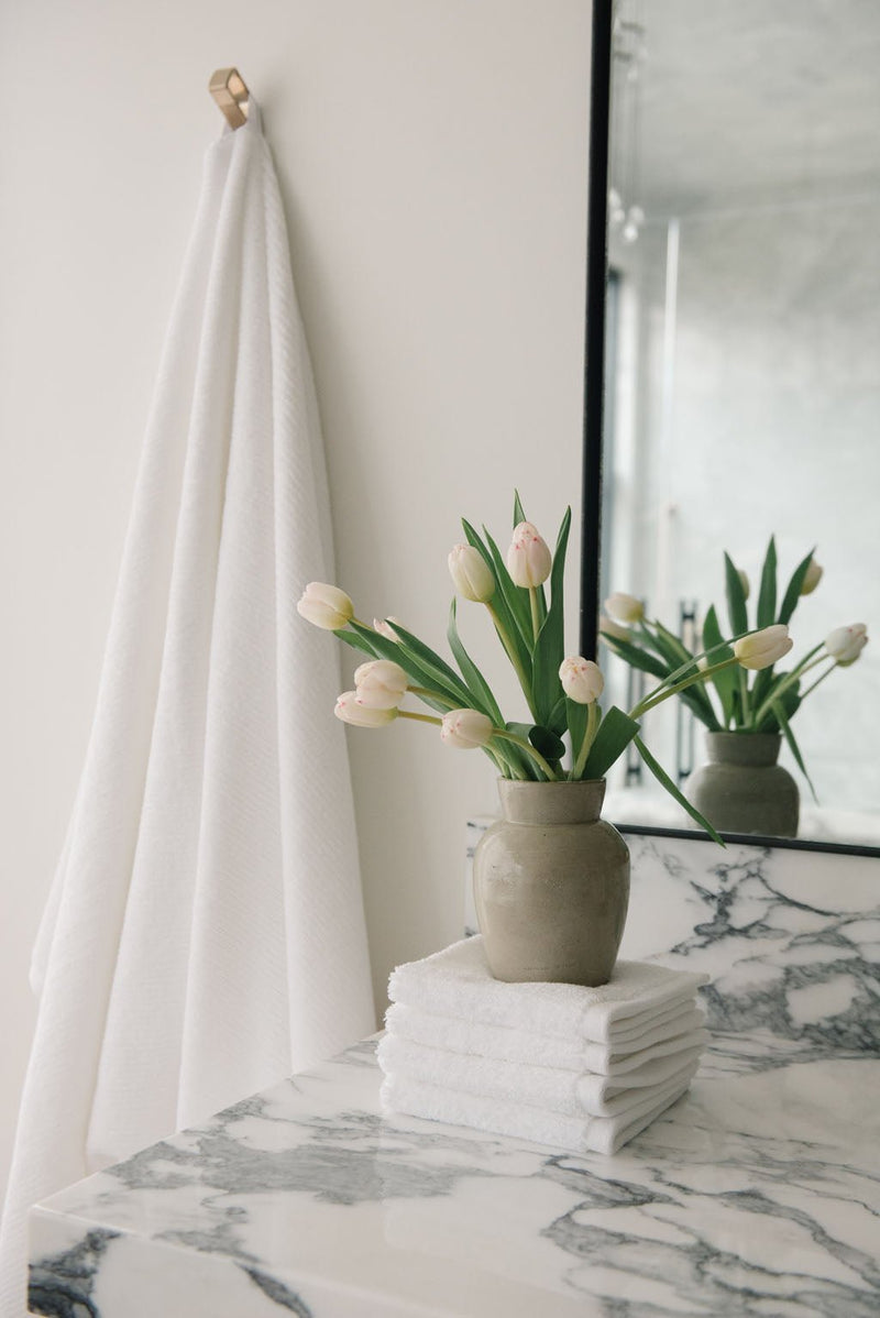 Ribbed Terry Wash Cloths in the color White. Photo of product taken in a bathroom featuring a white marble sink.
