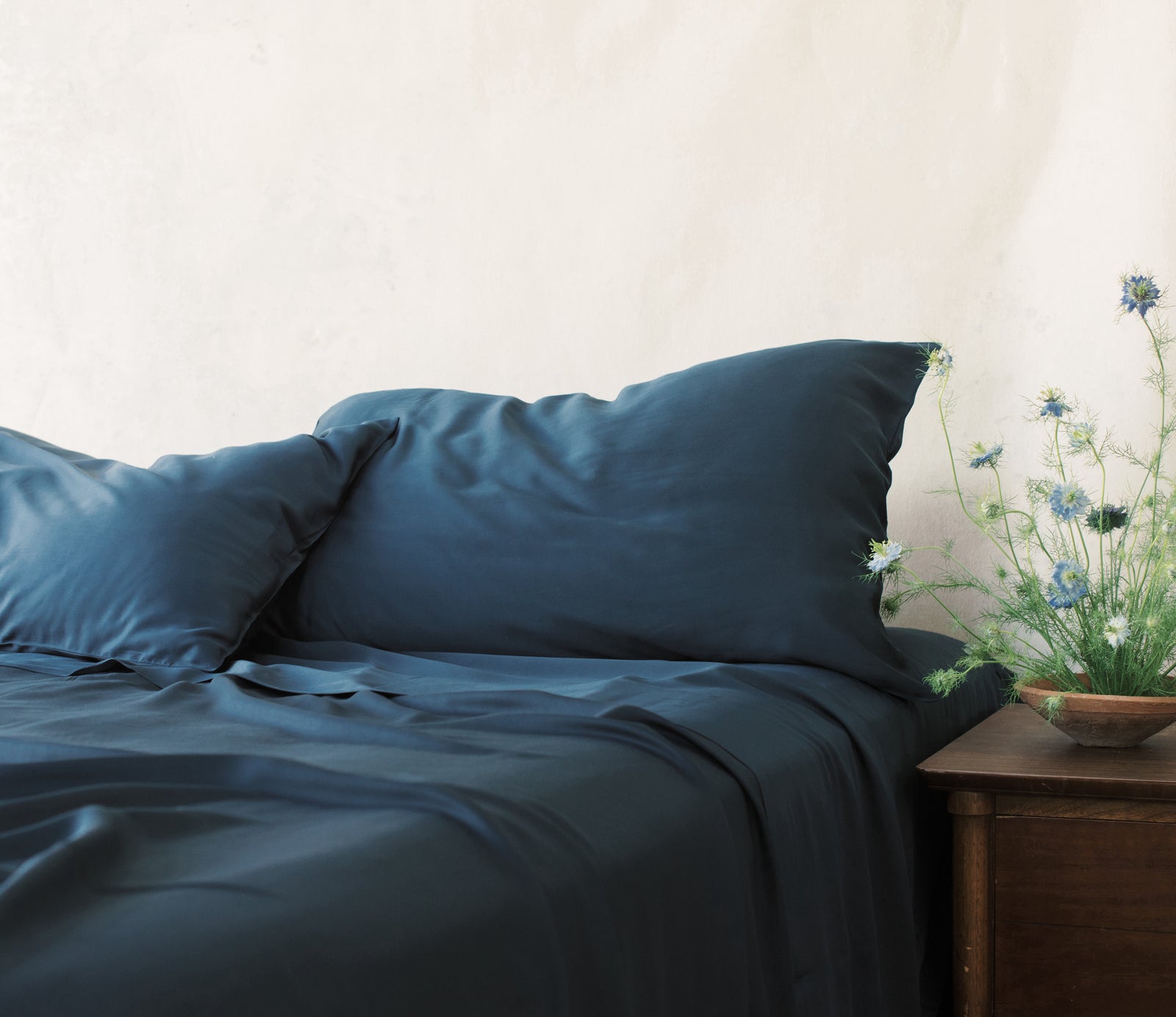 Bed with navy bedding and flowers on the nightstand standard/king/body