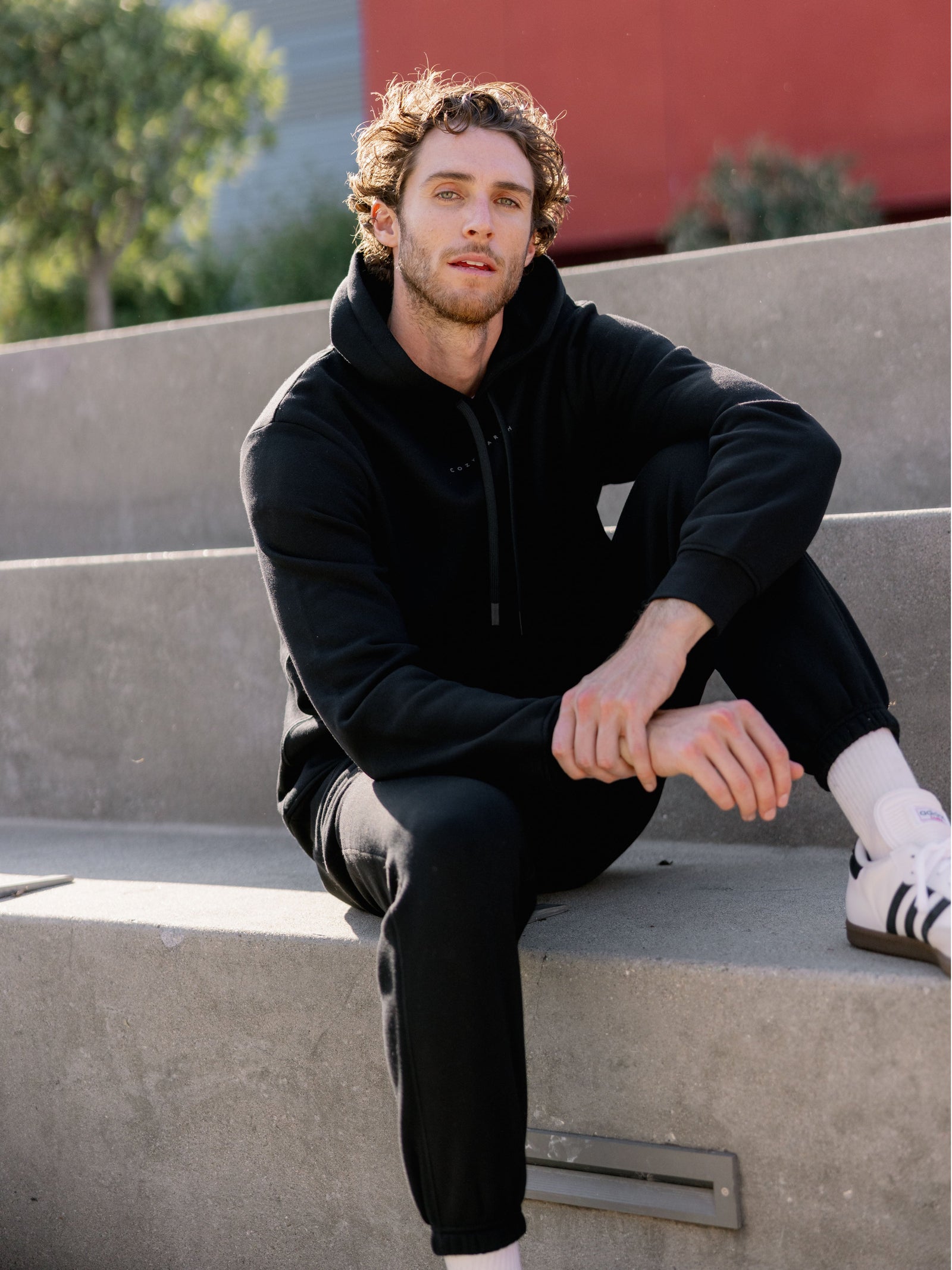 Man sitting outside in black cityscape hoodie and sweats 