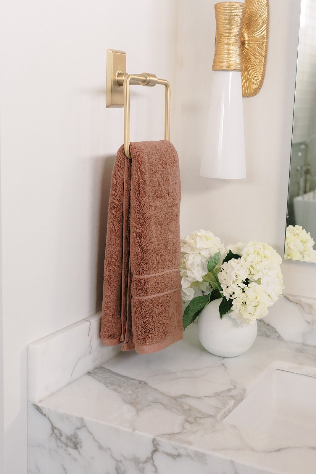 Premium Plush Hand Towel in the color Clay. Photo of Clay Premium Plush Hand Towel taken in a bathroom hanging from a gold hand towel ring 