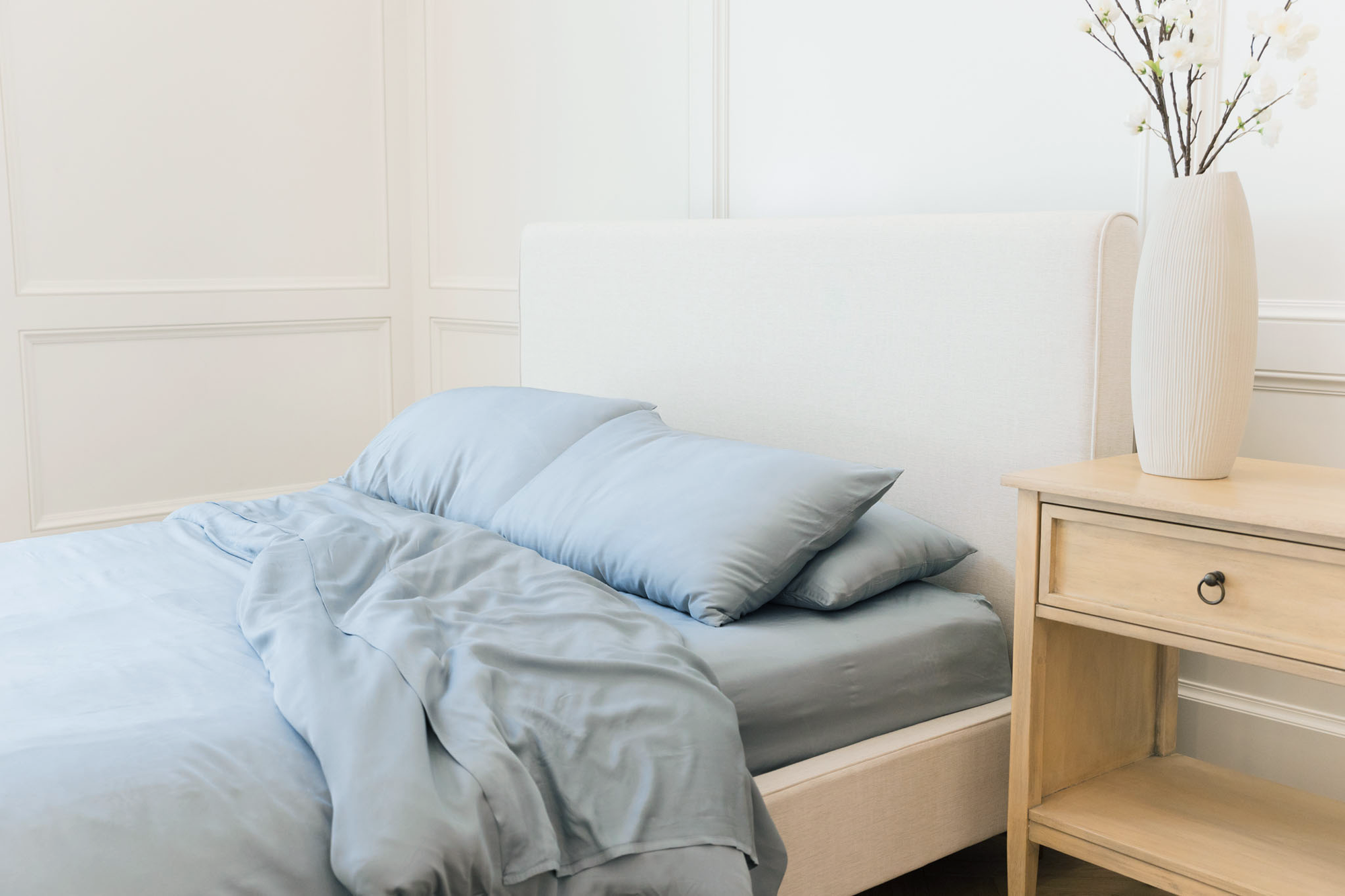 Bed made with harbor mist bedding in a white bedroom 