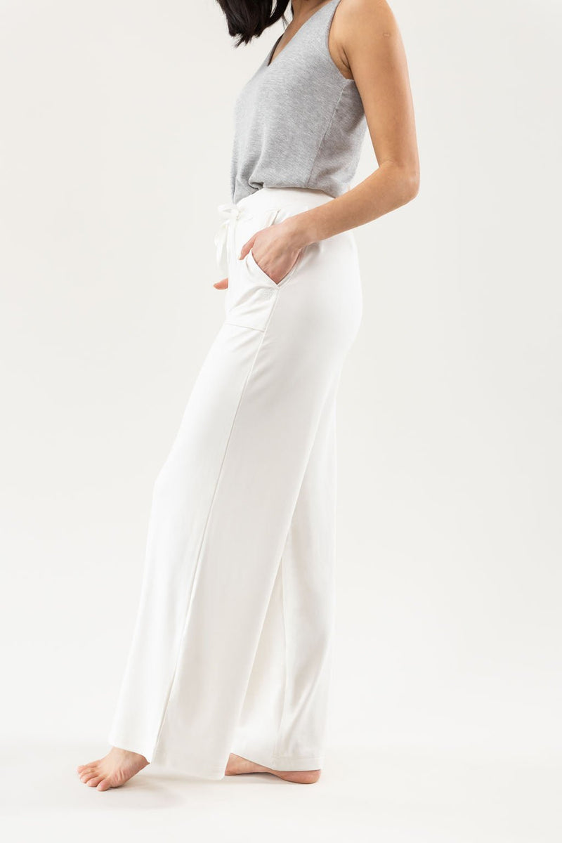 Ivory Bamboo Wide Leg Patch Pocket Pant modeled by a woman. The photo was taken in a high contrast setting, showing off the colors and lines of the pajamas.