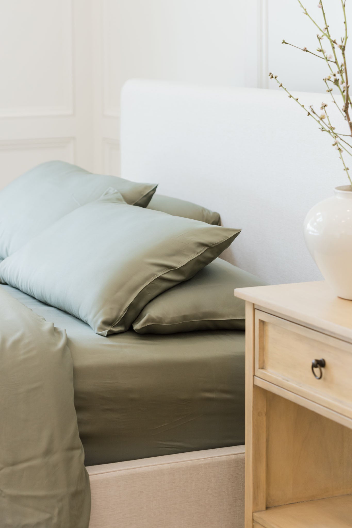 Side view of a bed with sage bedding and a nightstand standard/king/body