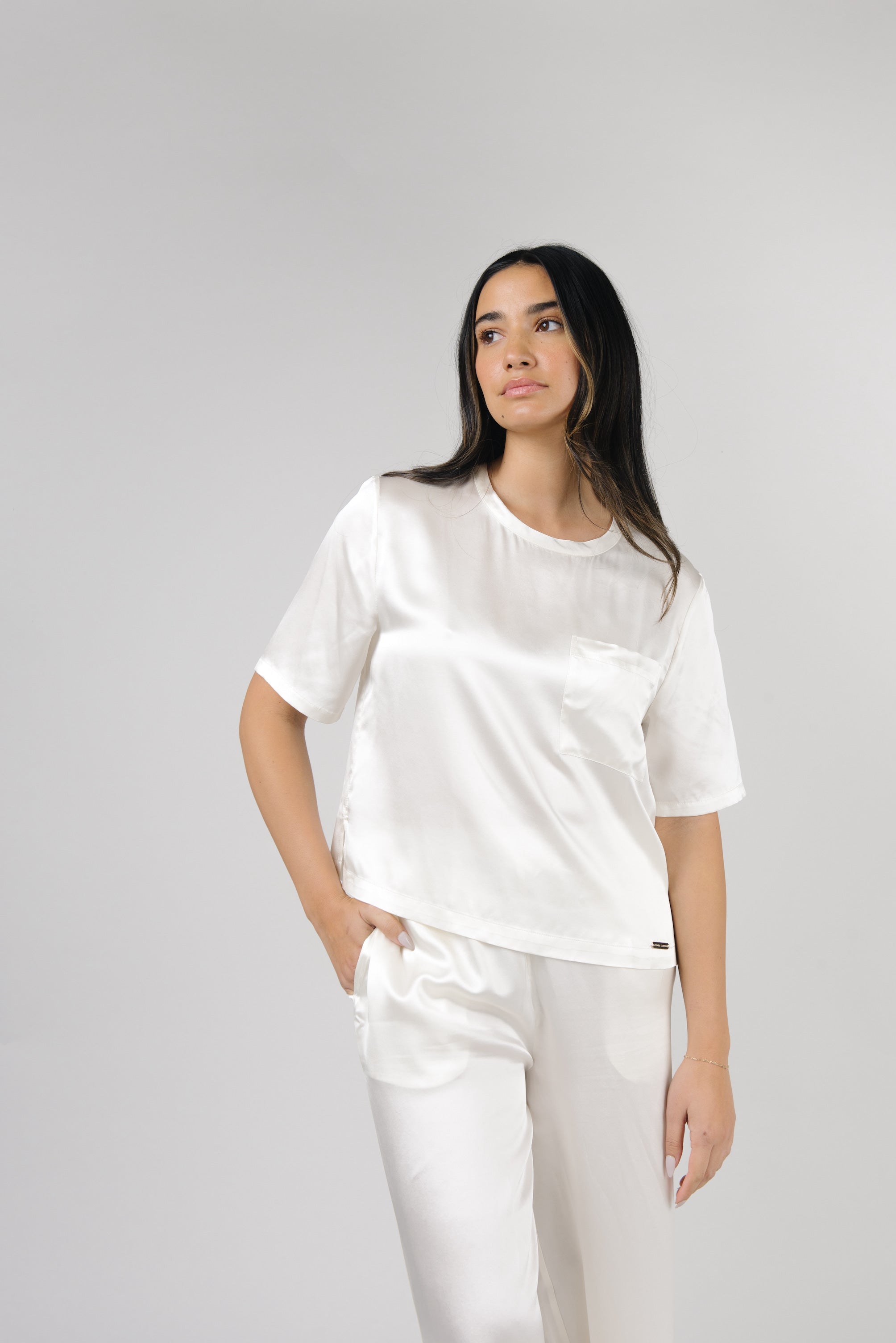 Ivory Serenity Silk Scoop Neck Tee modeled by a woman. The photo was taken in a high contrast setting, showing off the colors and lines of the tee. |Color: Ivory