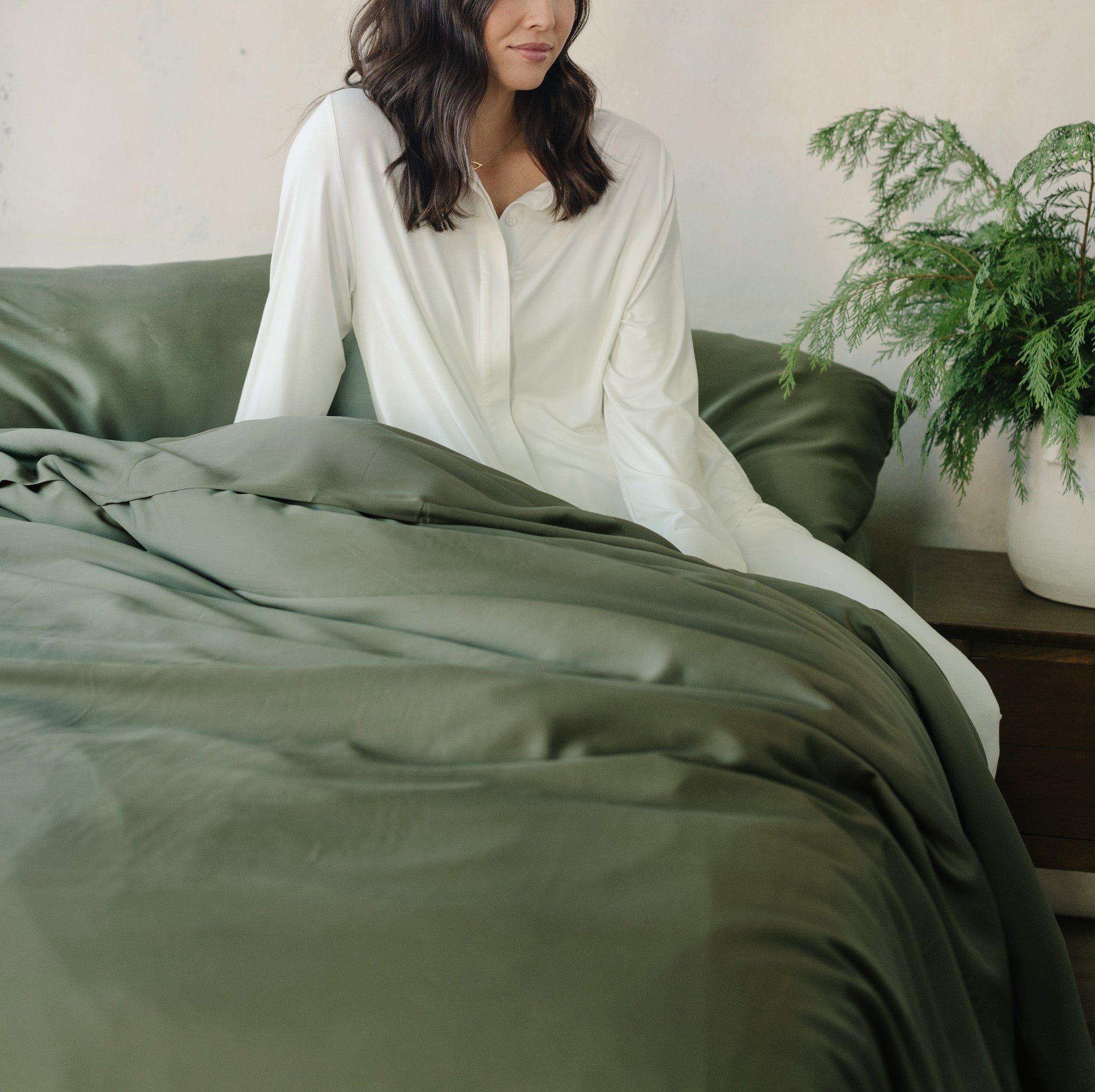 Woman sitting on bed with olive bedding 