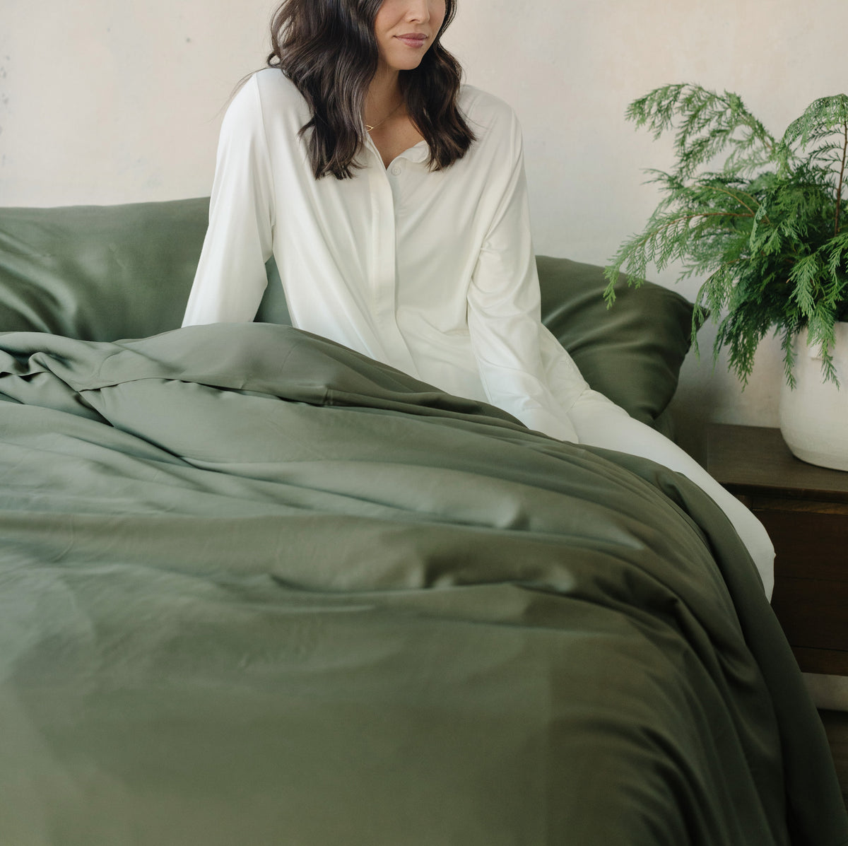 Woman in white pajamas sitting on bed with olive bedding |Color:Olive