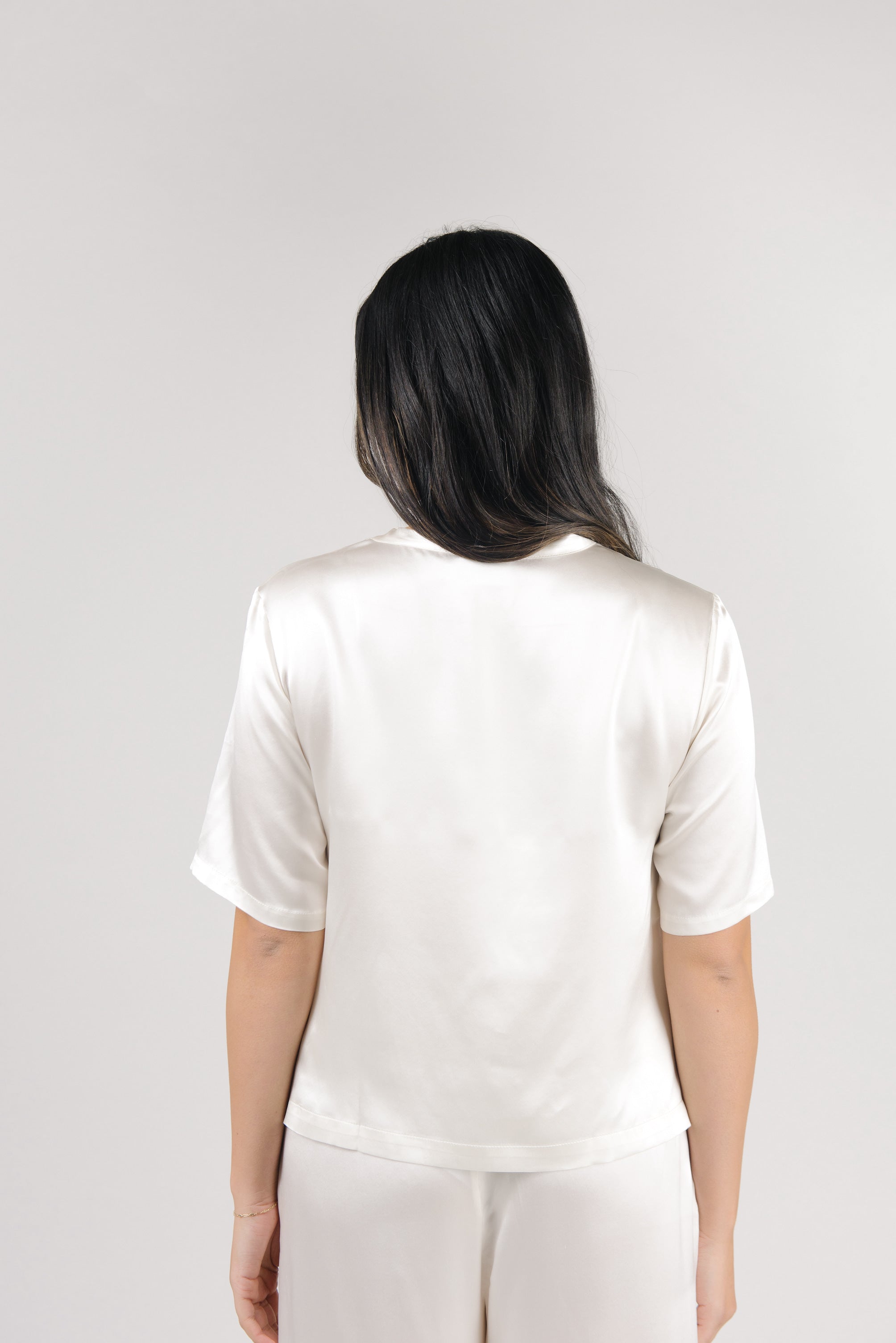 Ivory Serenity Silk Scoop Neck Tee modeled by a woman. The photo was taken in a high contrast setting, showing off the colors and lines of the tee. |Color: Ivory