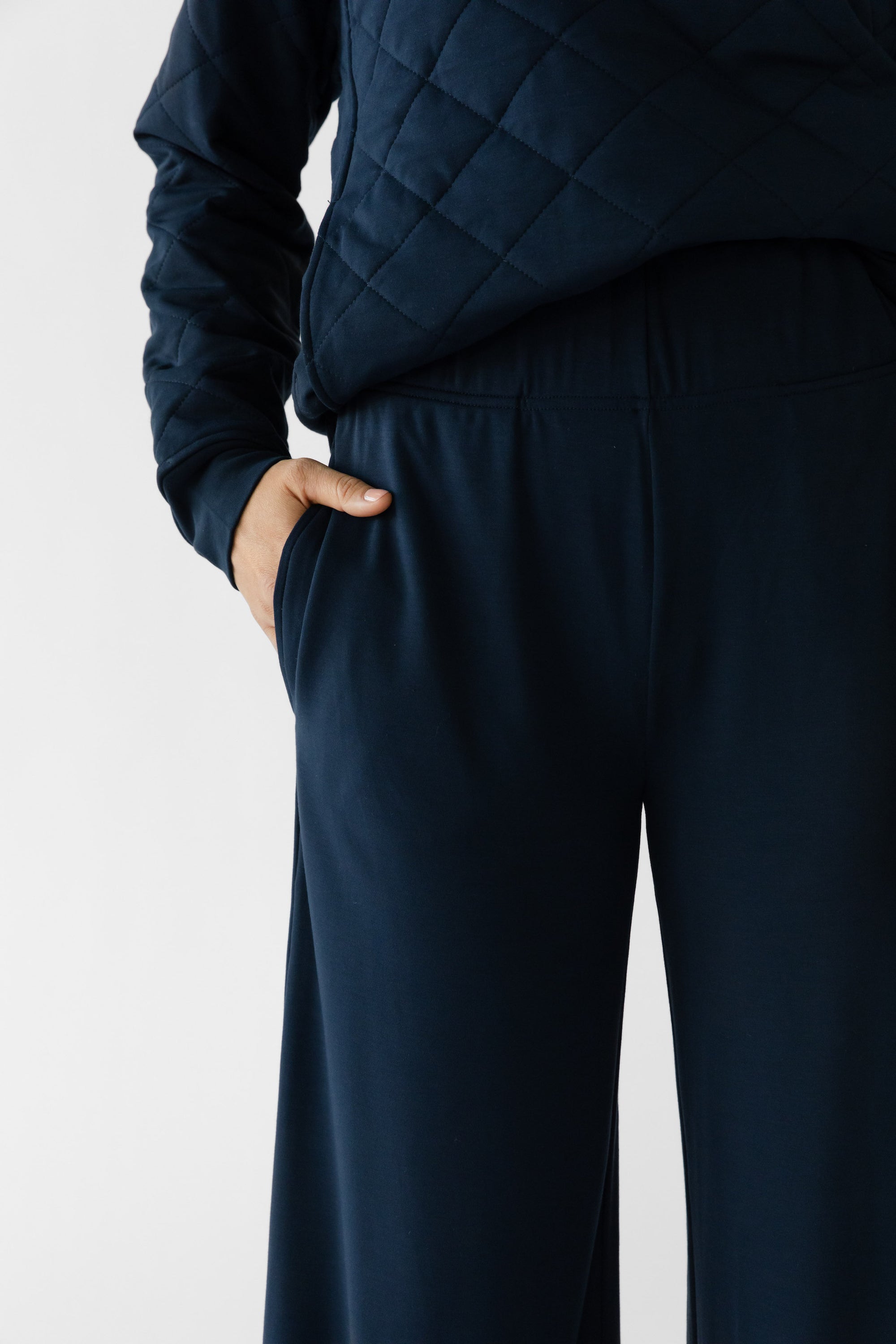 A woman stands in a relaxed pose wearing navy lounge pants set from Cozy Earth, featuring the Women's Ultra-Soft Bamboo Wide Leg Pull On Pant TALL. 