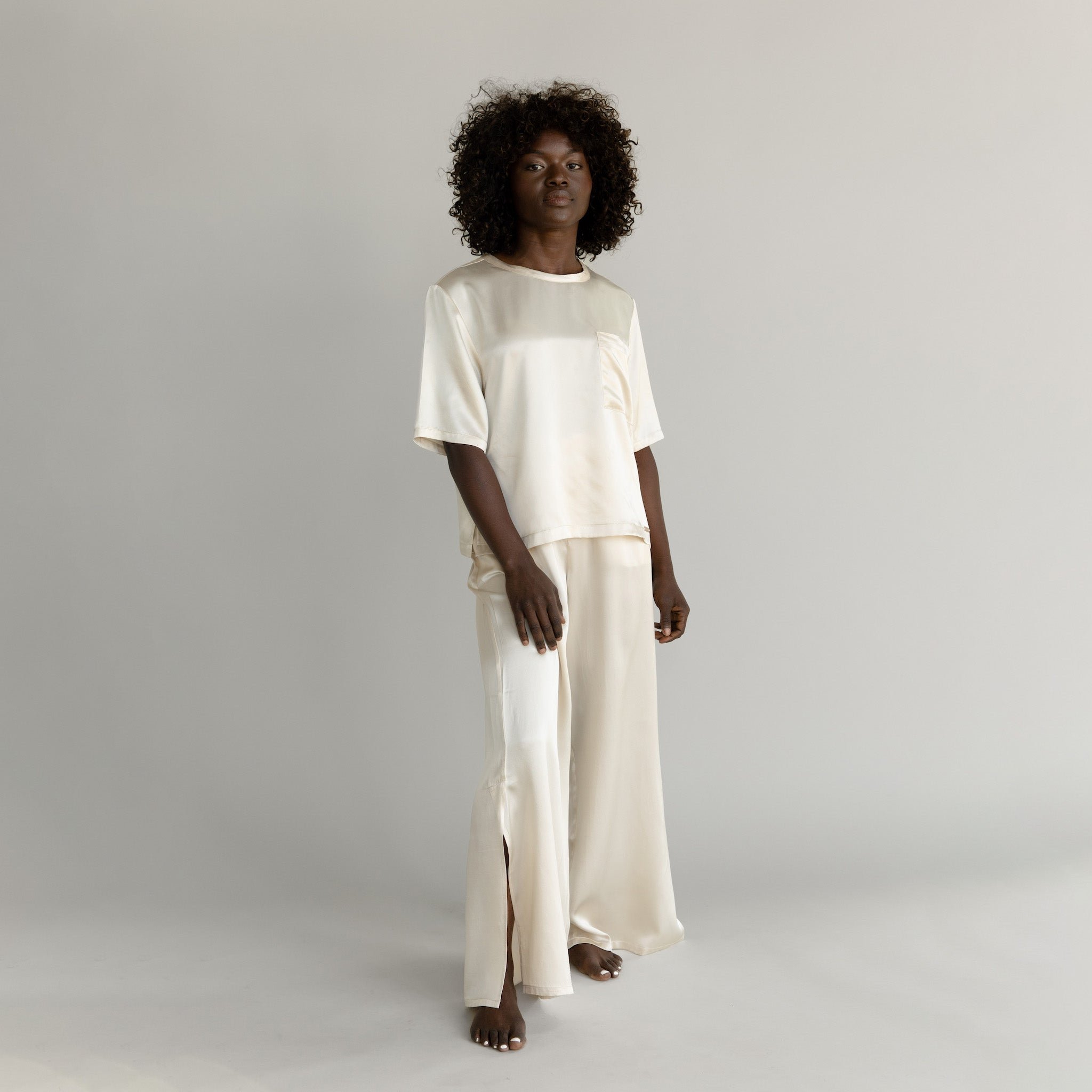 Champagne Serenity Silk Scoop Neck Tee modeled by a woman. The photo was taken in a high contrast setting, showing off the colors and lines of the tee. |Color: Champagne
