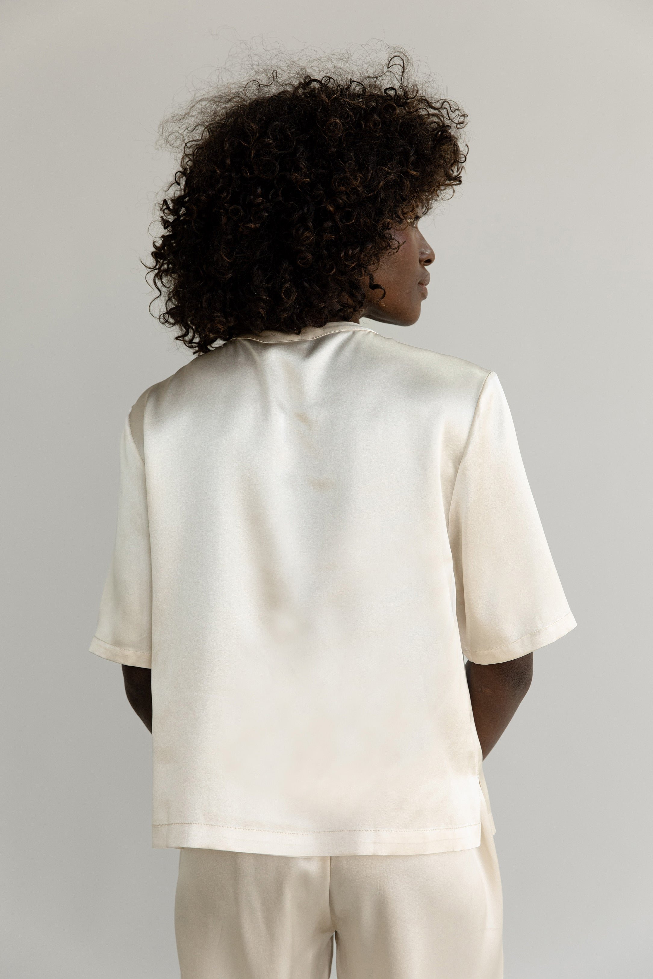 Champagne Serenity Silk Scoop Neck Tee modeled by a woman. The photo was taken in a high contrast setting, showing off the colors and lines of the tee. 