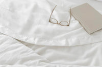 bamboo blanket spread over a bed with glasses and a book on top