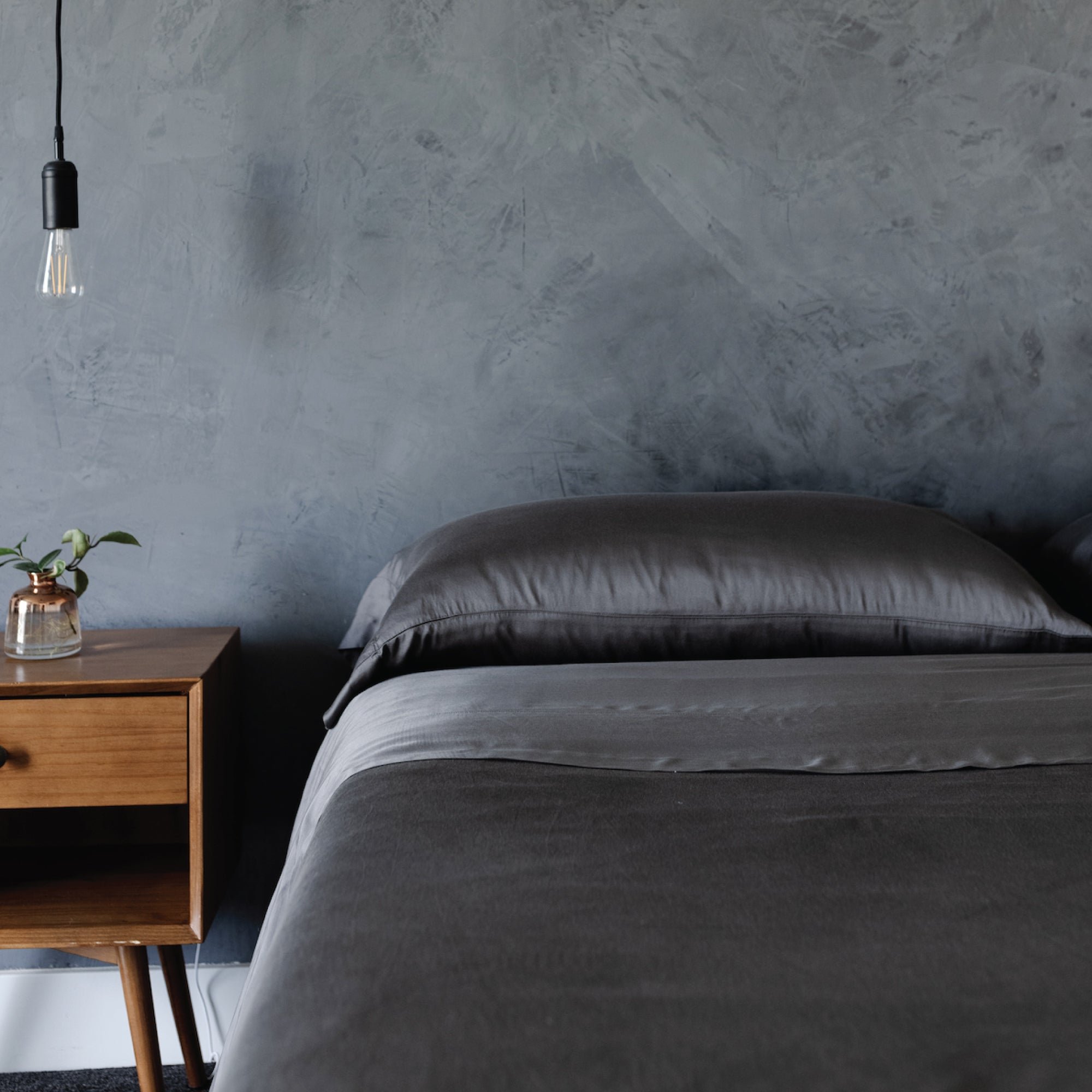 Dark bedroom with a bed with charcoal bedding 
