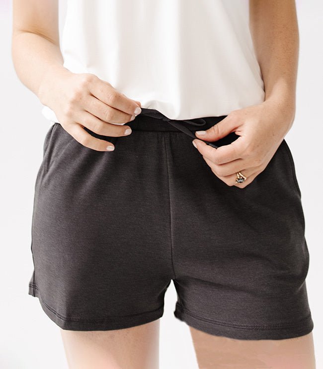 Person wearing Cozy Earth Brushed Bamboo Jogger Shorts in dark grey and a white top on a light background 
