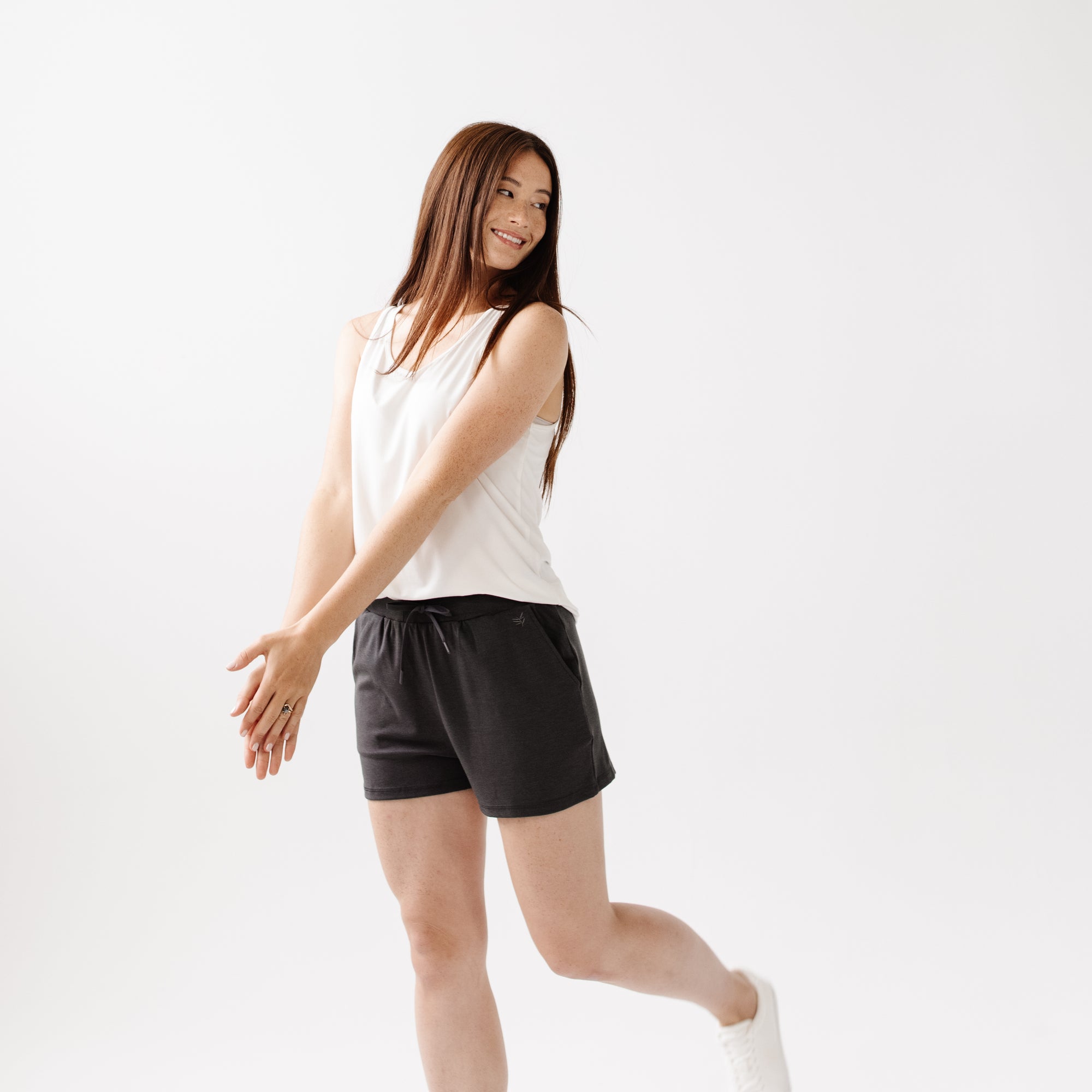 Person wearing Cozy Earth Brushed Bamboo Jogger Shorts in dark grey and a white top on a light background 