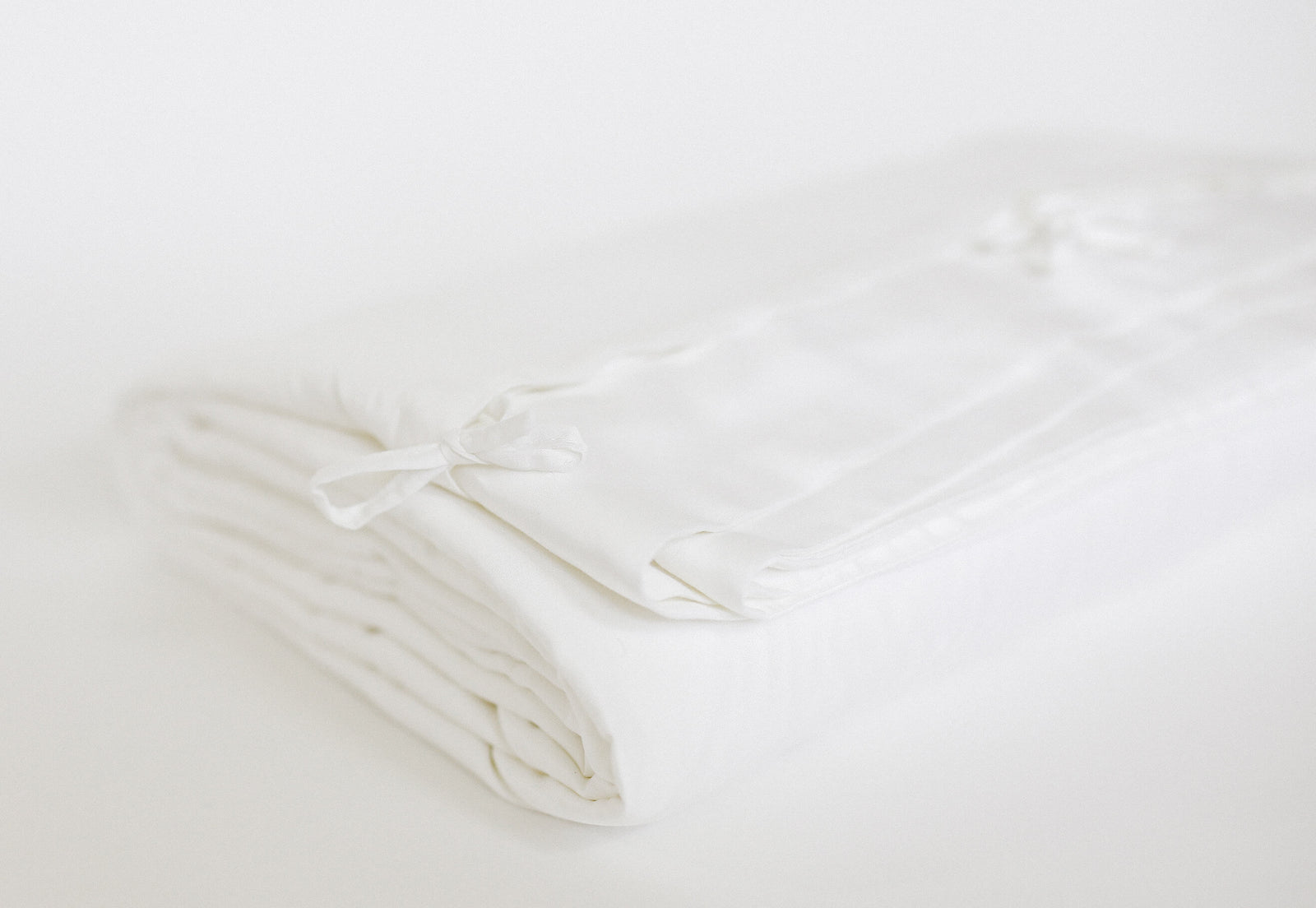 Folded white duvet cover at an angle with white background 