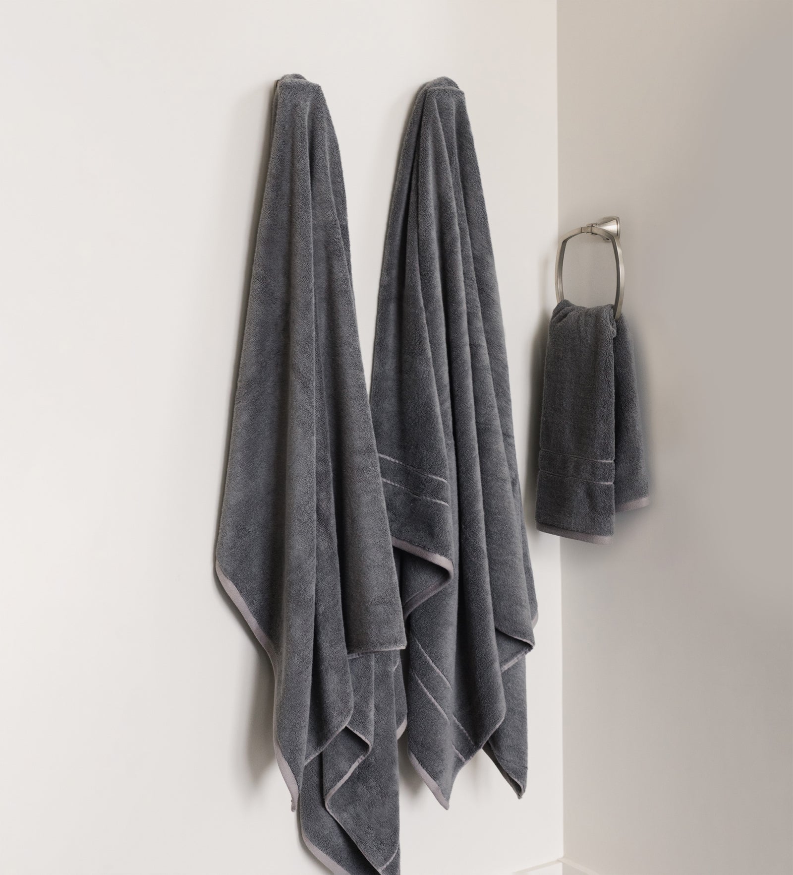 Premium Plush Bath Sheets in the color charcoal. Photo of Premium Plush Bath sheets taken in a bathroom showing the towels which are hung from a towel rack. 