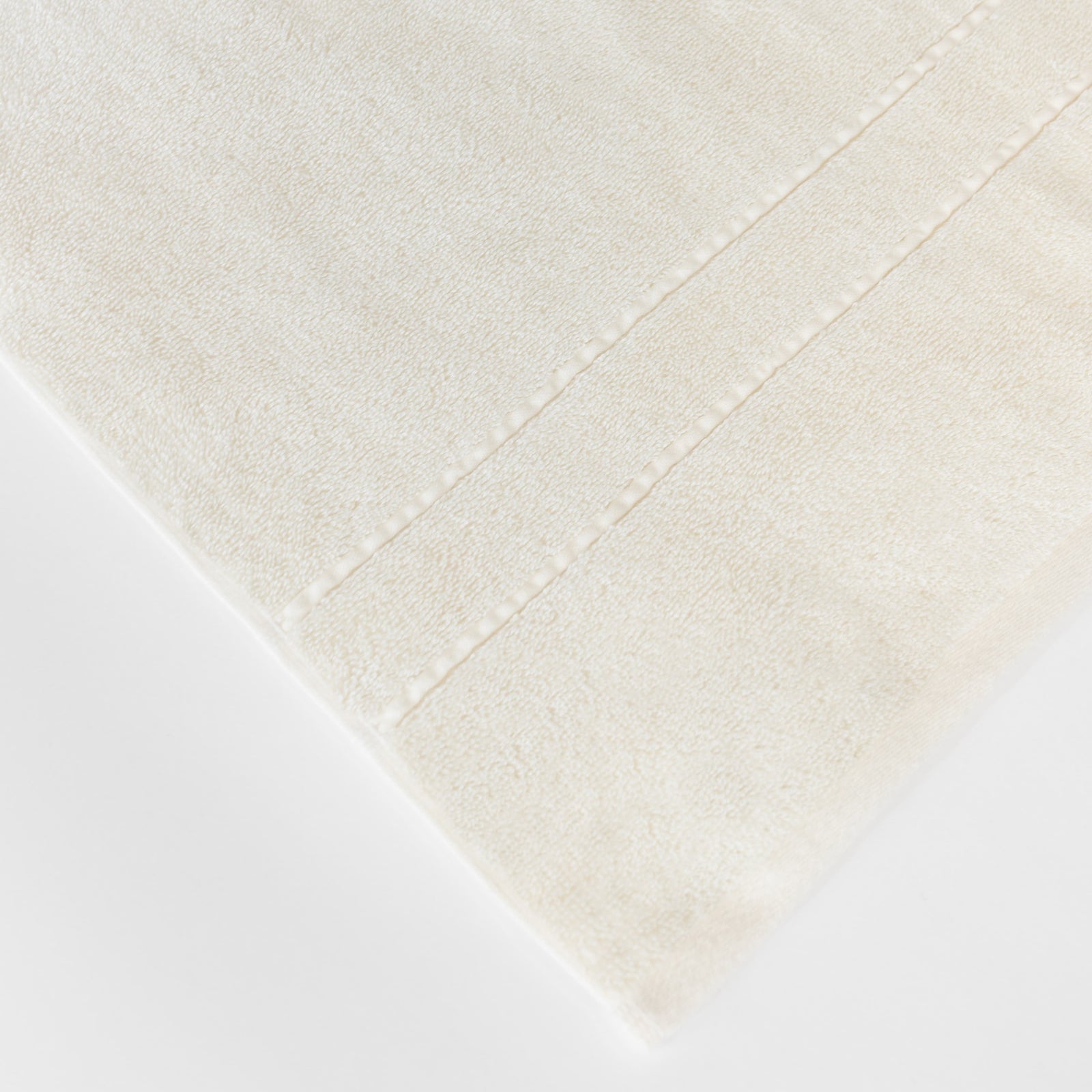 Premium Plush Bath Towels in the color Creme. Photo of Premium Plush Bath Towels taken on a white background showing only the corner of the towel. 