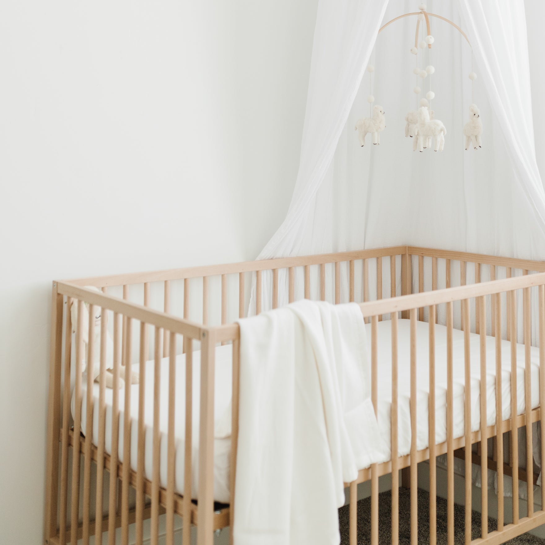 Wooden crib with white baby blanket draped over the side