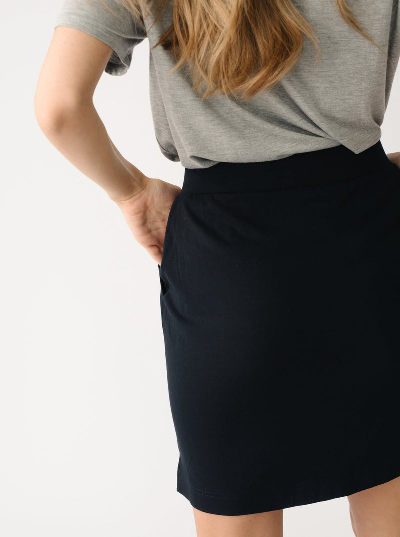 Person wearing a Cozy Earth Brushed Bamboo Patch Pocket Skirt in black on a white background