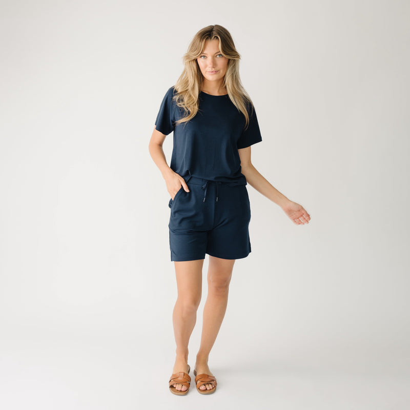 Woman wearing a navy t-shirt and navy Cozy Earth Brushed Bamboo Mid-Length Shorts shorts on a plain background