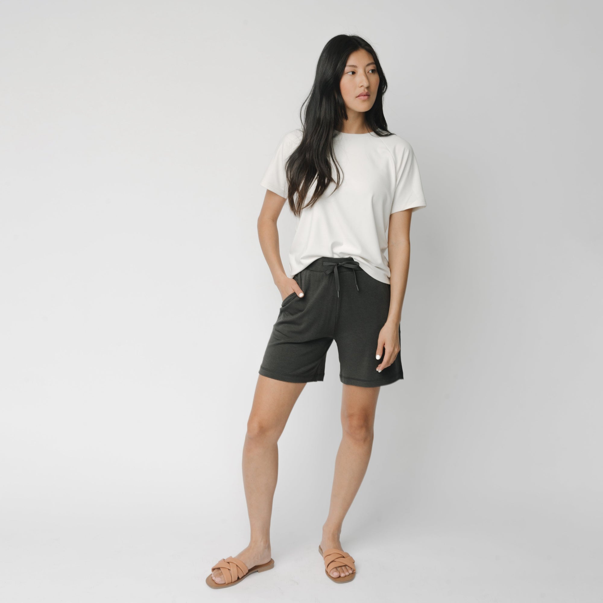 Woman wearing a white t-shirt and grey Cozy Earth Brushed Bamboo Mid-Length Shorts shorts on a plain background 