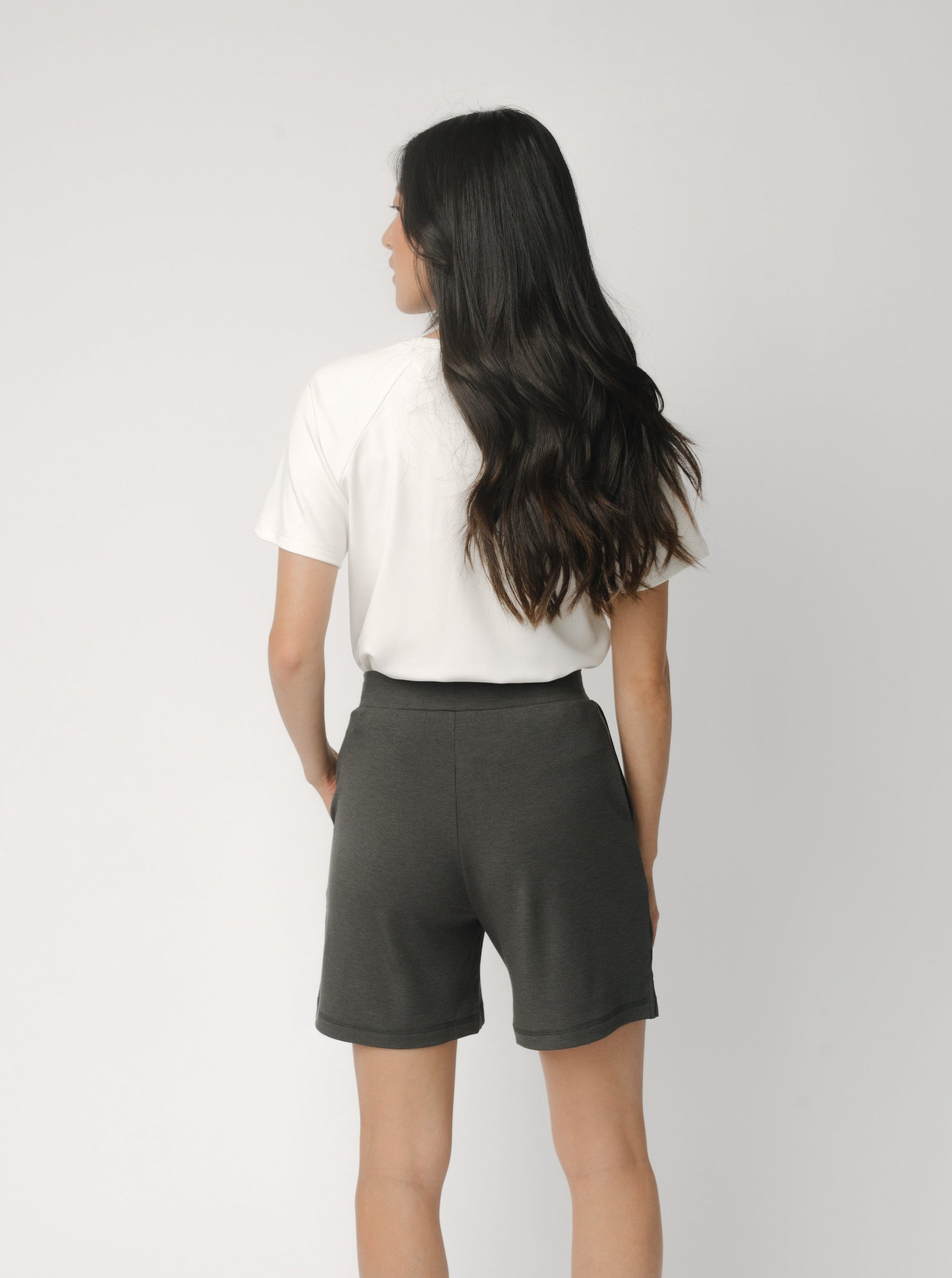 Woman wearing a white t-shirt and grey Cozy Earth Brushed Bamboo Mid-Length Shorts shorts on a plain background 