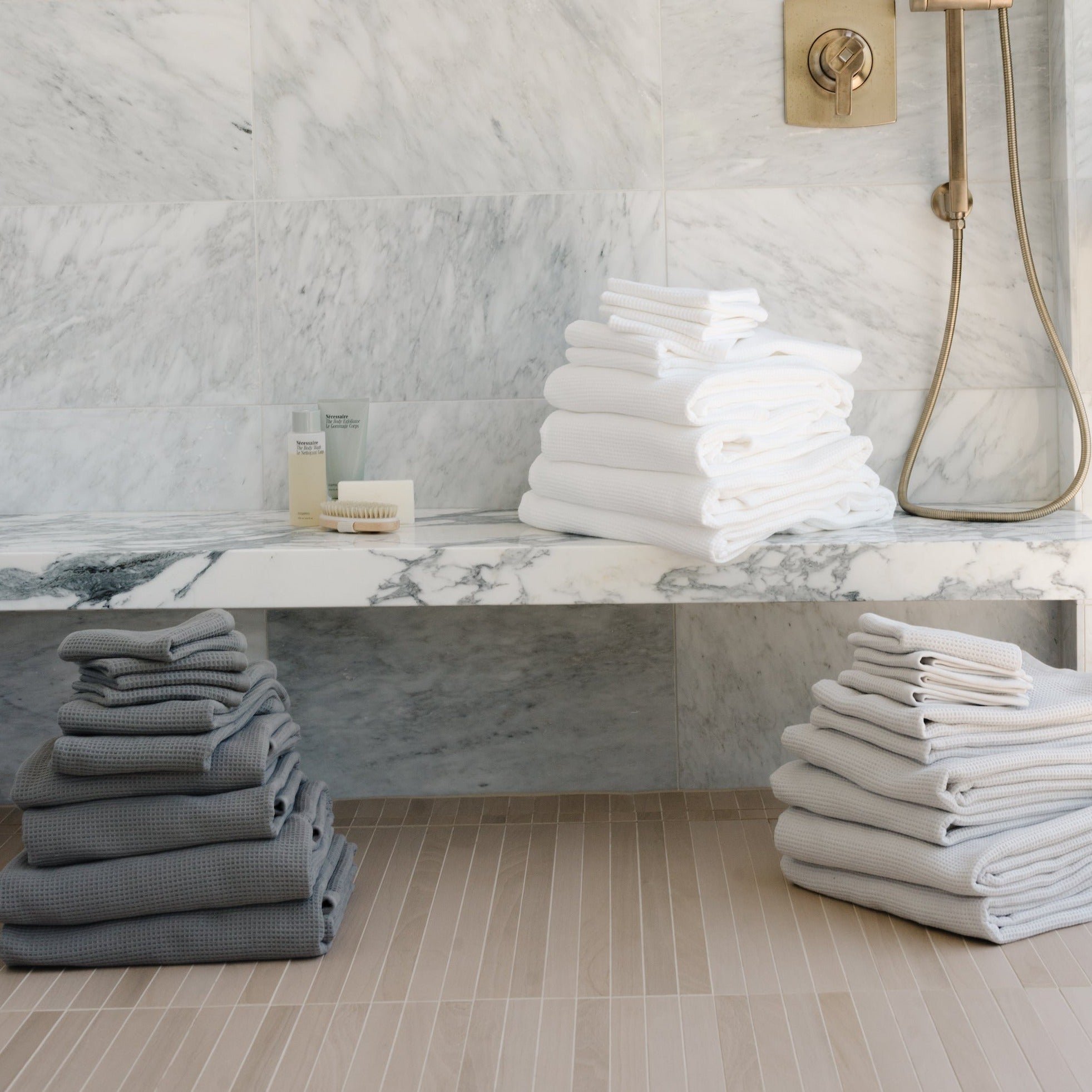 Complete Waffle Bath Bundle in the colors Charcoal, White, and Light Grey. Photo of Charcoal, White, and Light Grey Complete Waffle Bath Bundle taken while towels rest on bathroom floor
