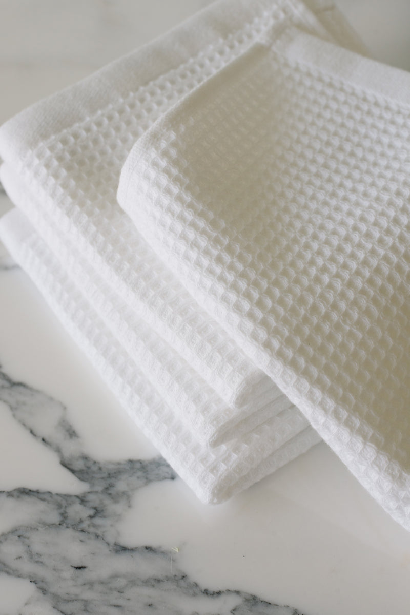 White Waffle Wash Cloths neatly folded. The photo was taken with the cloths resting on a white marble sink.