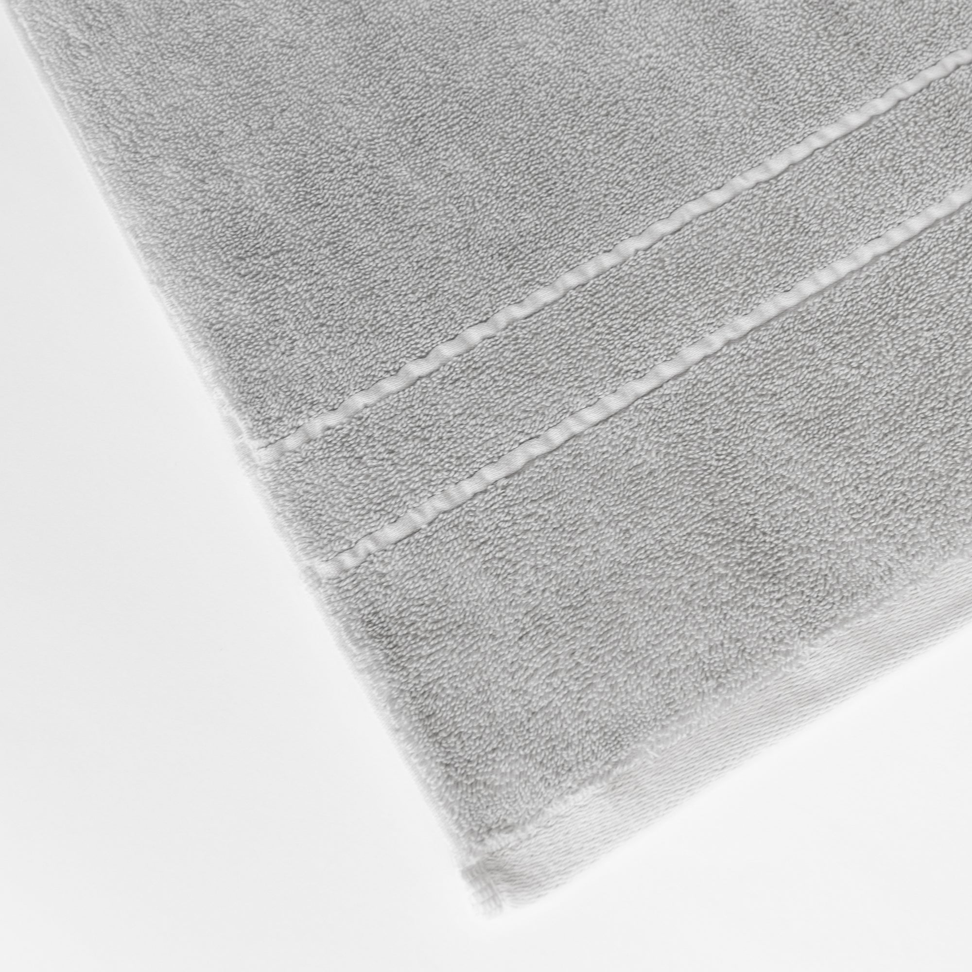 Premium Plush Bath Towels in the color Light Grey. Photo of Premium Plush Bath Towels taken on a white background showing only the corner of the towel. 
