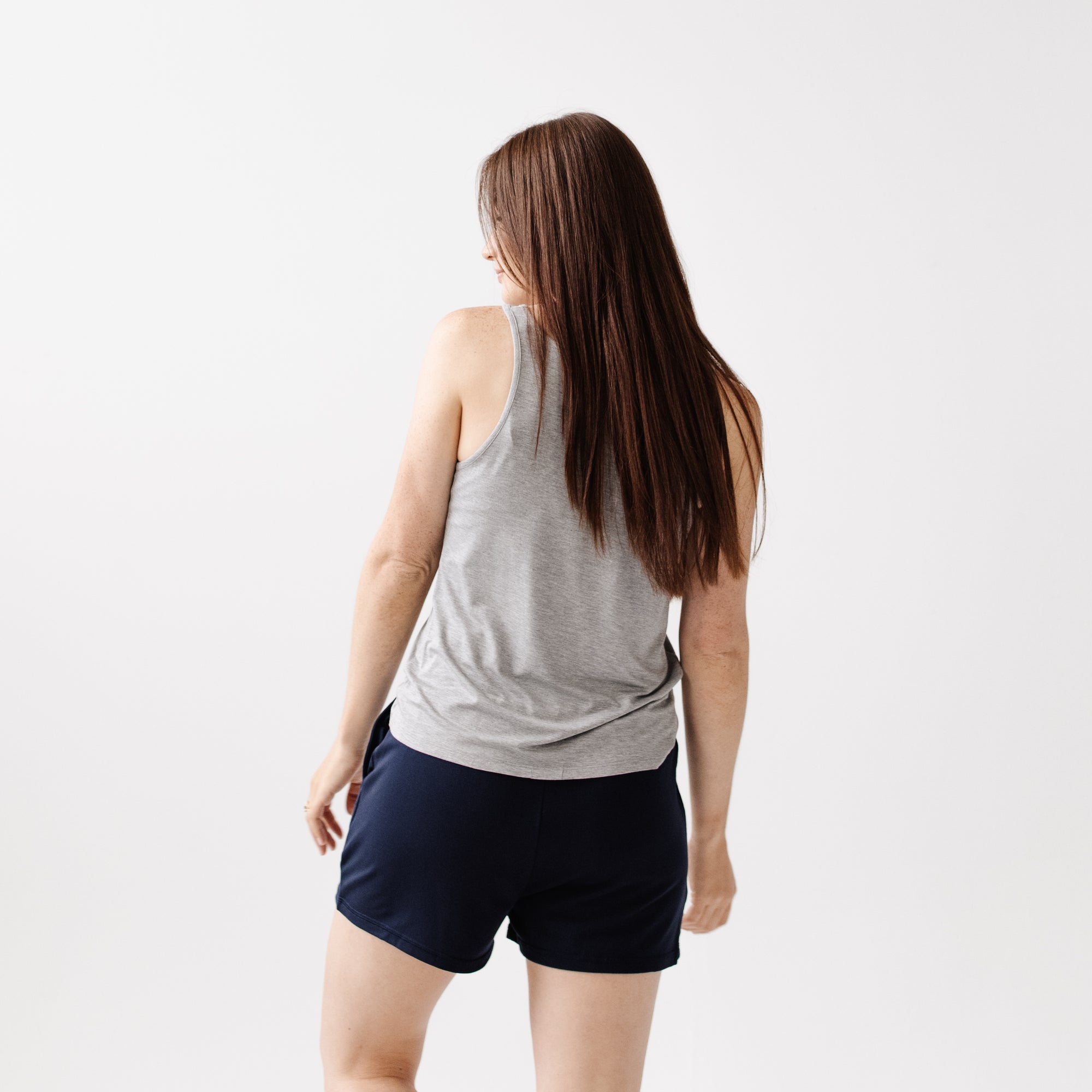 A woman facing backwards wearing Cozy Earth Brushed Bamboo Jogger Shorts in navy and a gray top on a light background 