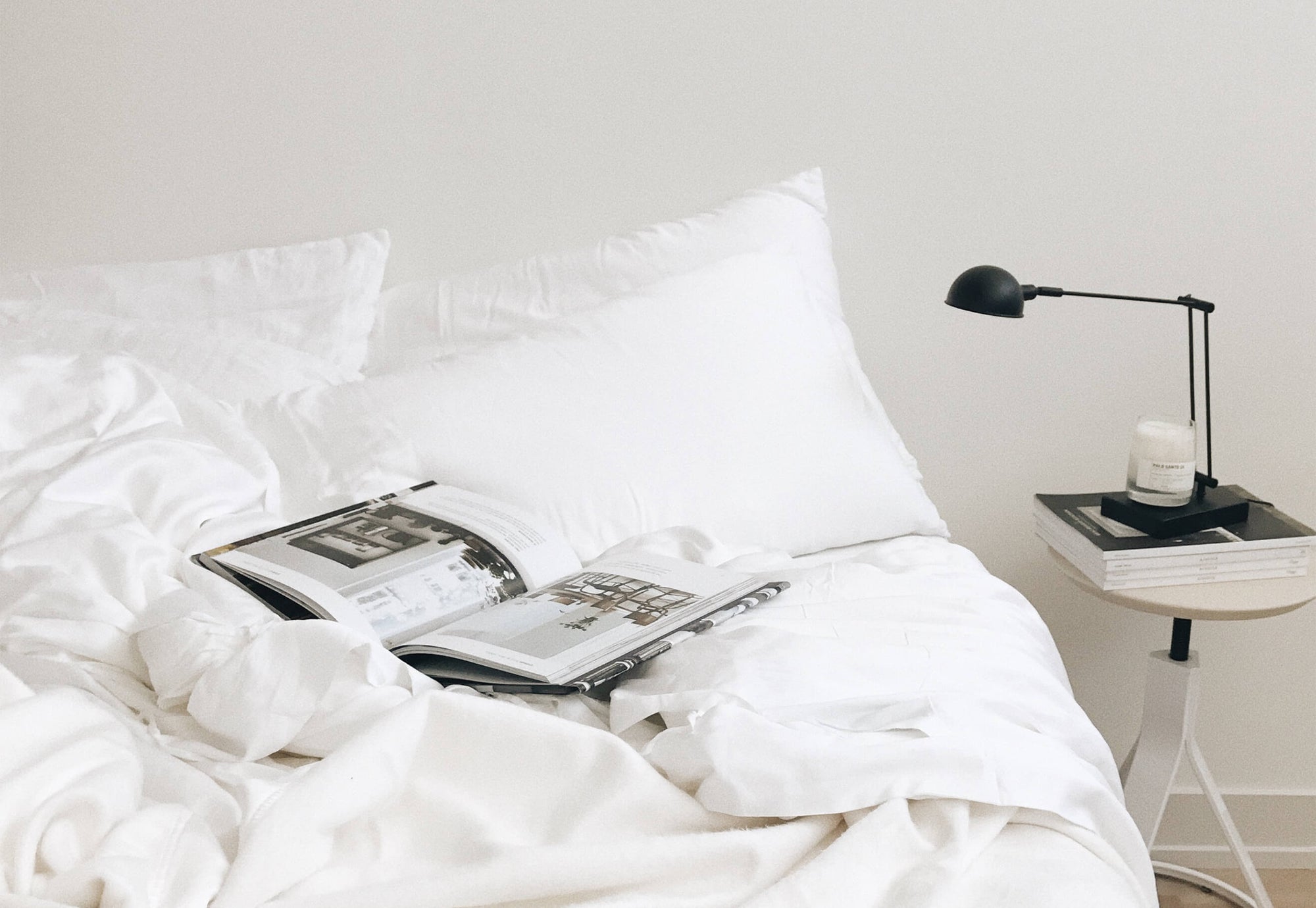 Bed with white bedding, standard/king pillows, and a book on top 