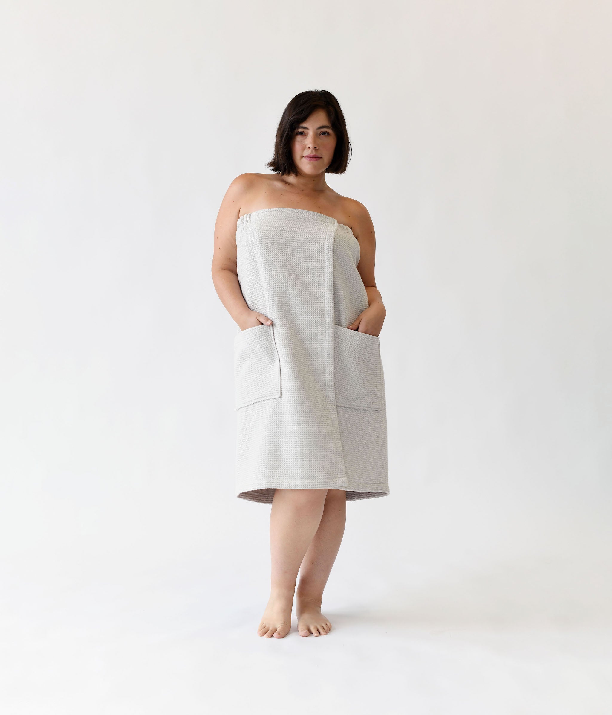 Light Grey Waffle Bath Wrap. The bath wrap is shown being worn by a woman. Photo was taken with a white background.|Color:Light Grey