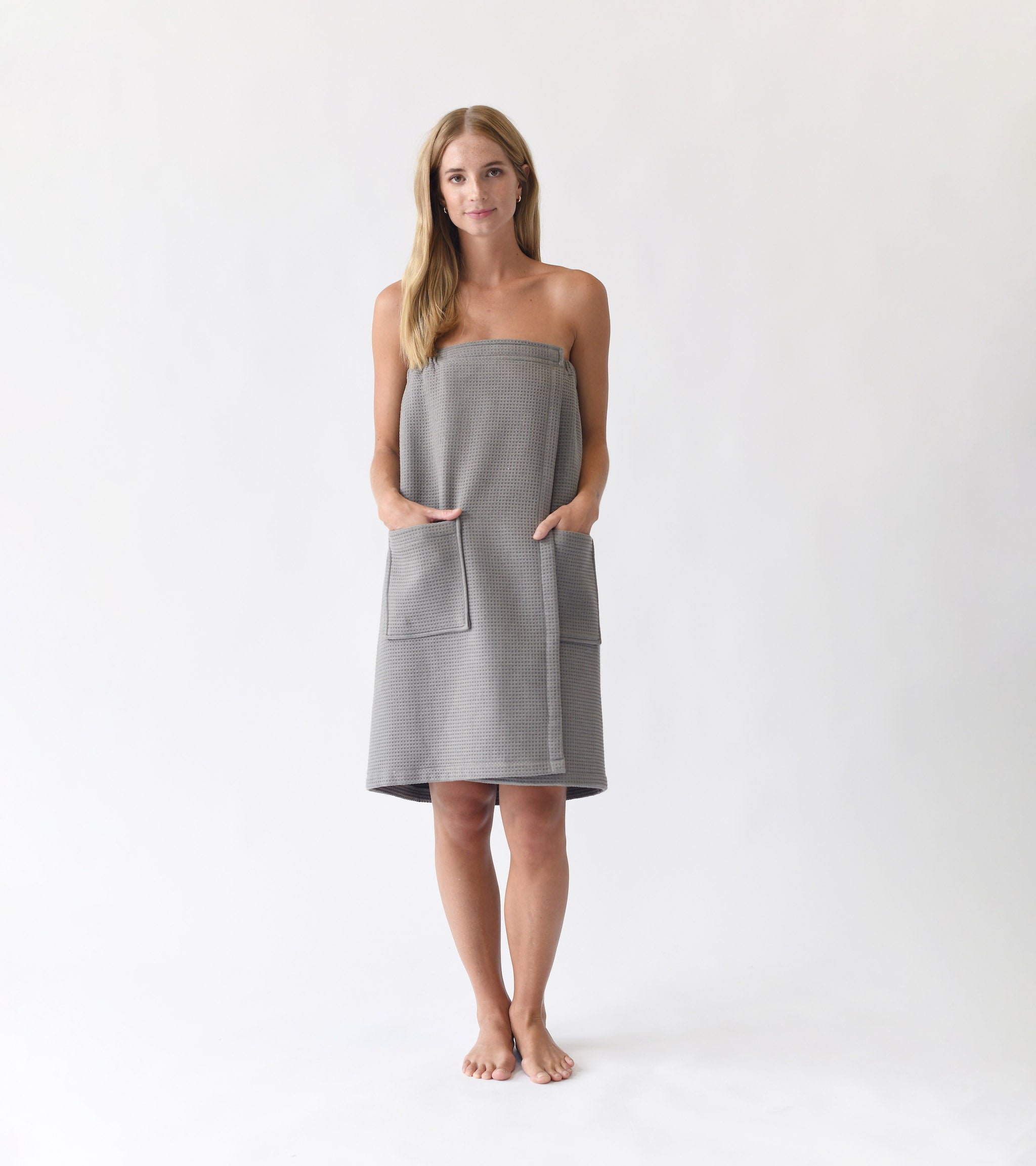 Charcoal Waffle Bath Wrap. The bath wrap is shown being worn by a woman. Photo was taken with a white background.|Color:Charcoal